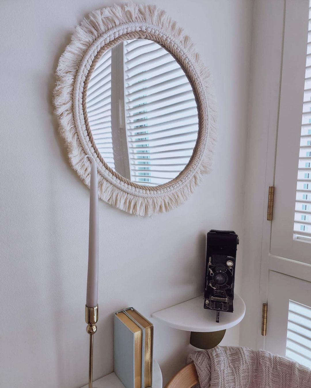 Purr-fectly Styled Nook - Round mirror with fringed frame, white wall, window with blinds, vintage camera, gold candlestick