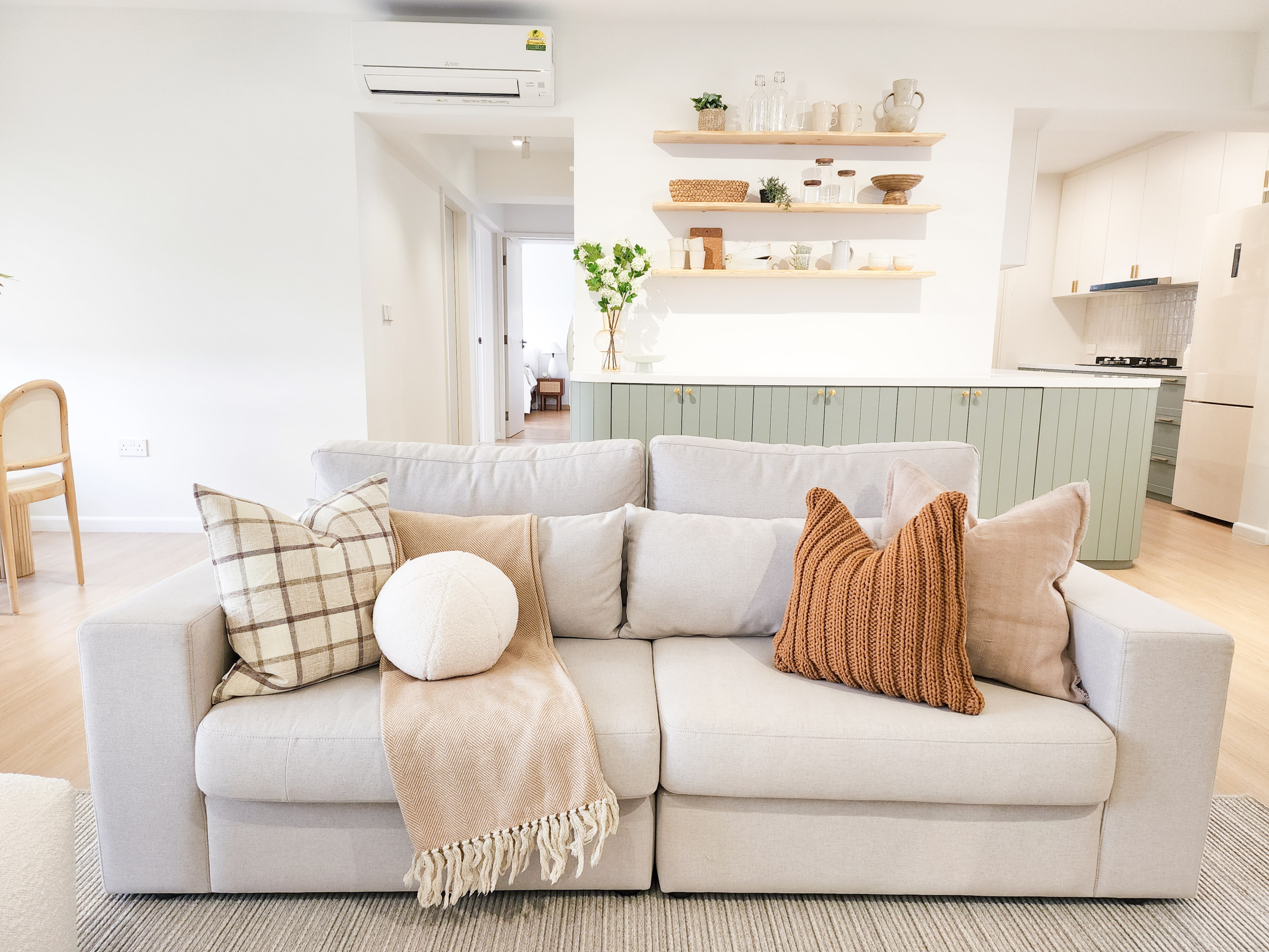 Curves & more - Light beige sectional sofa, beige and brown throw blanket, plaid and solid pillows, wooden chair, light