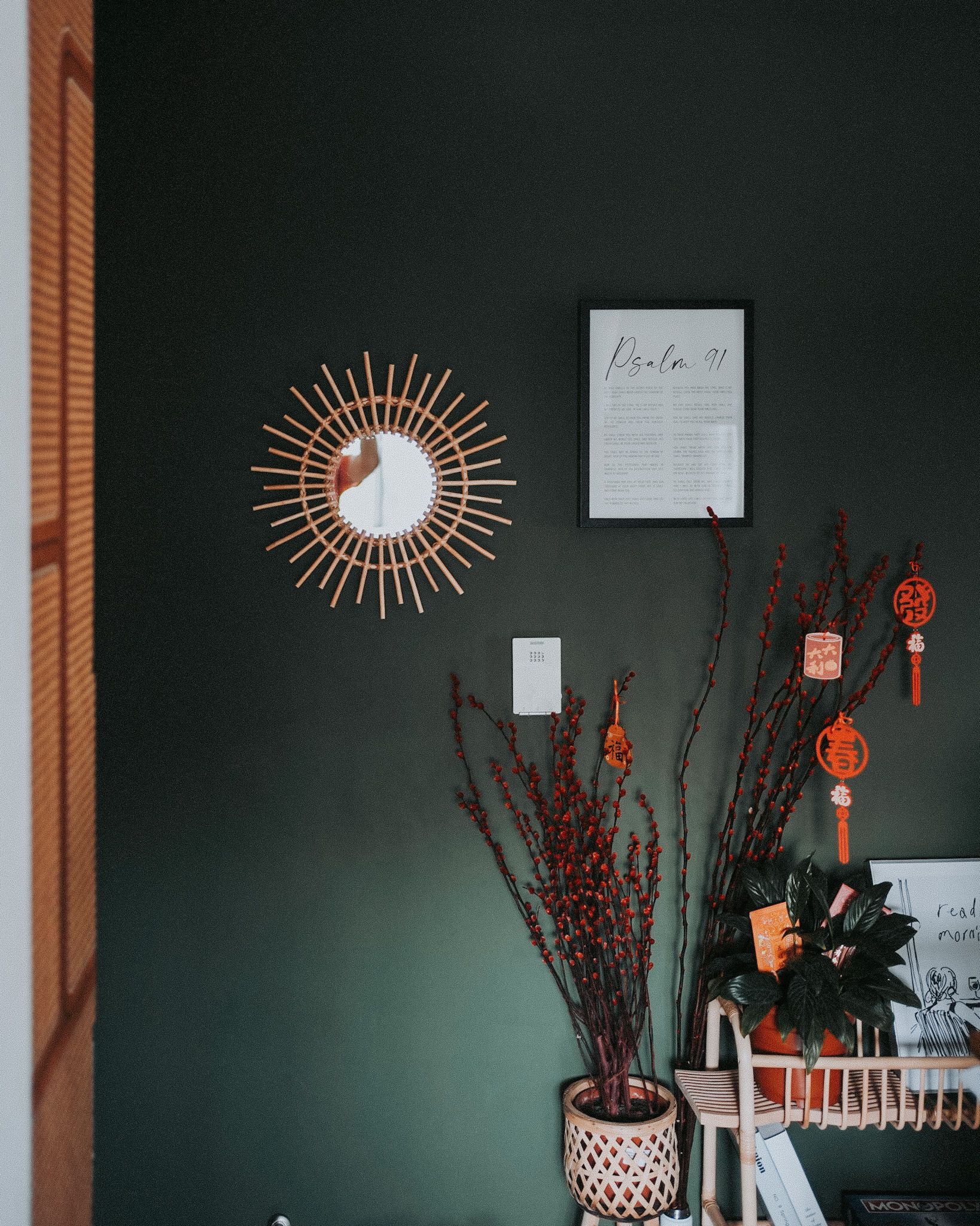 Nostalgia meets postmodernism - Sunburst mirror, dark green wall, decorative arrangement, red branches, Chinese lanterns