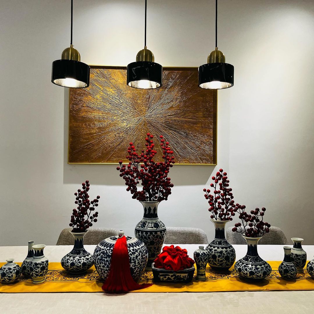 Grandeur and porcelain - vibrant red berries, black and white porcelain vases, golden abstract painting, modern dining table