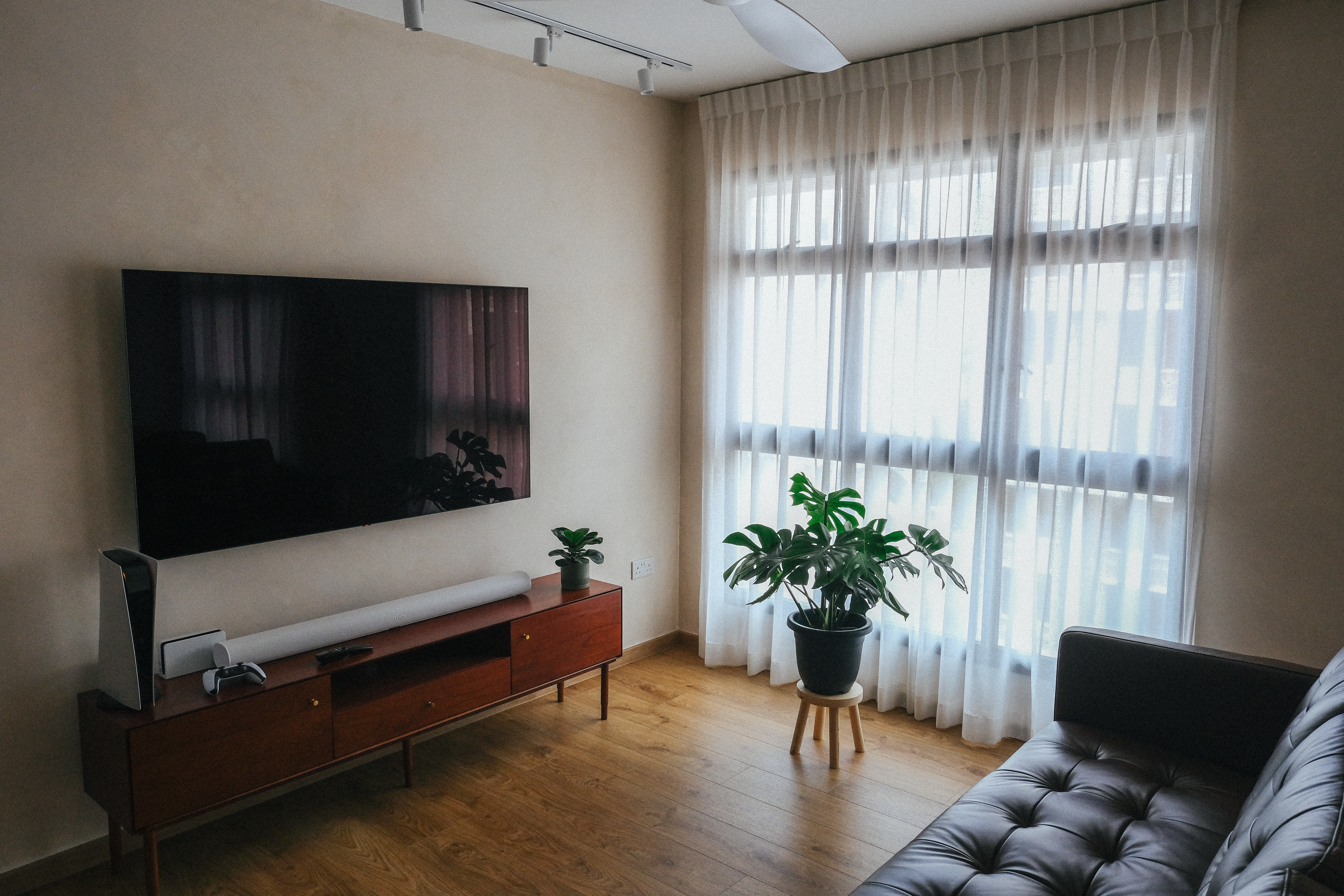 A cosy Mid-Century Mediterranean inspired abode - Large flat-screen TV, wooden entertainment center, potted plants, beige