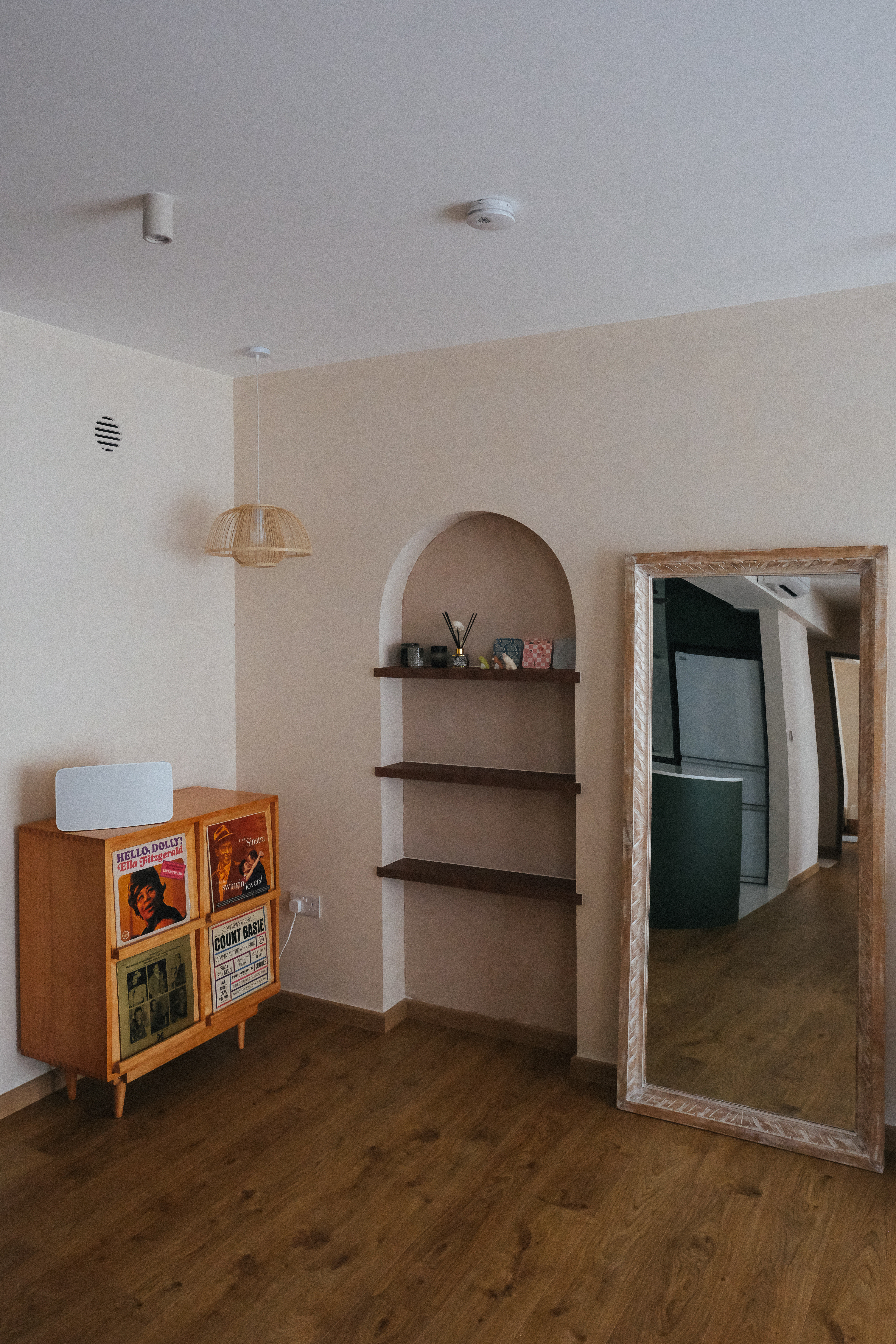 A cosy Mid-Century Mediterranean inspired abode - Wooden cabinet, vintage posters, arched shelf, modern light fixture