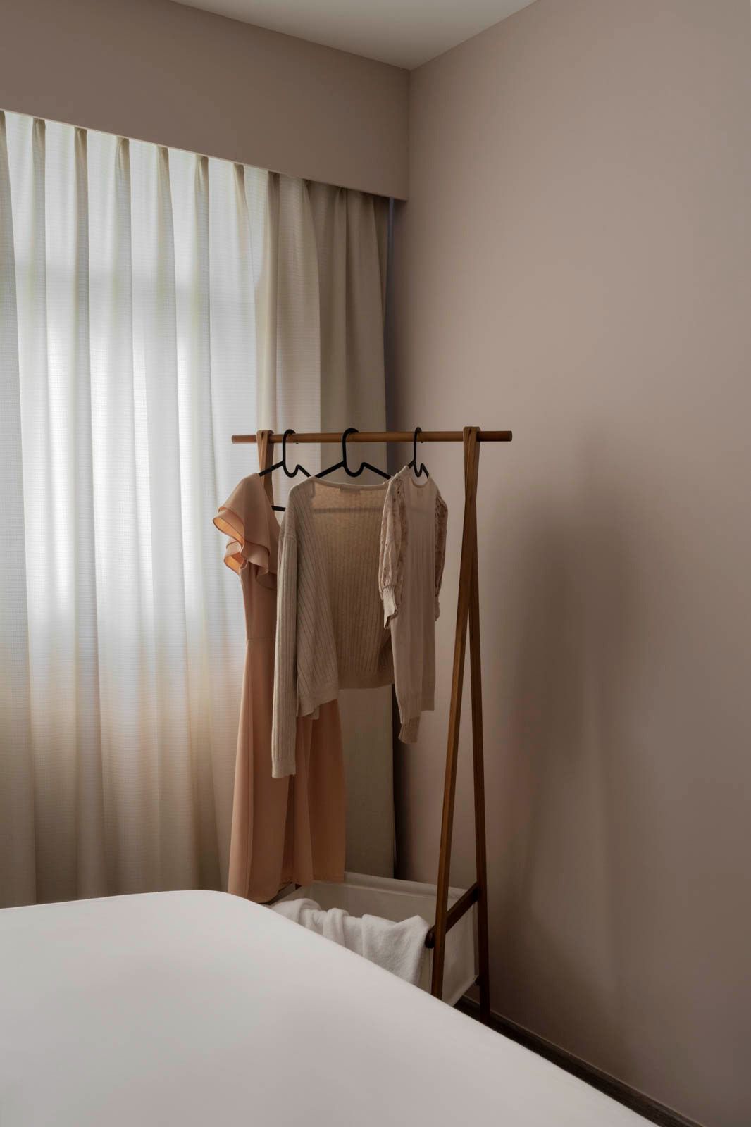Our master bedroom is kept to the necessities - Soft, neutral-toned curtains frame a window, allowing gentle light to filter