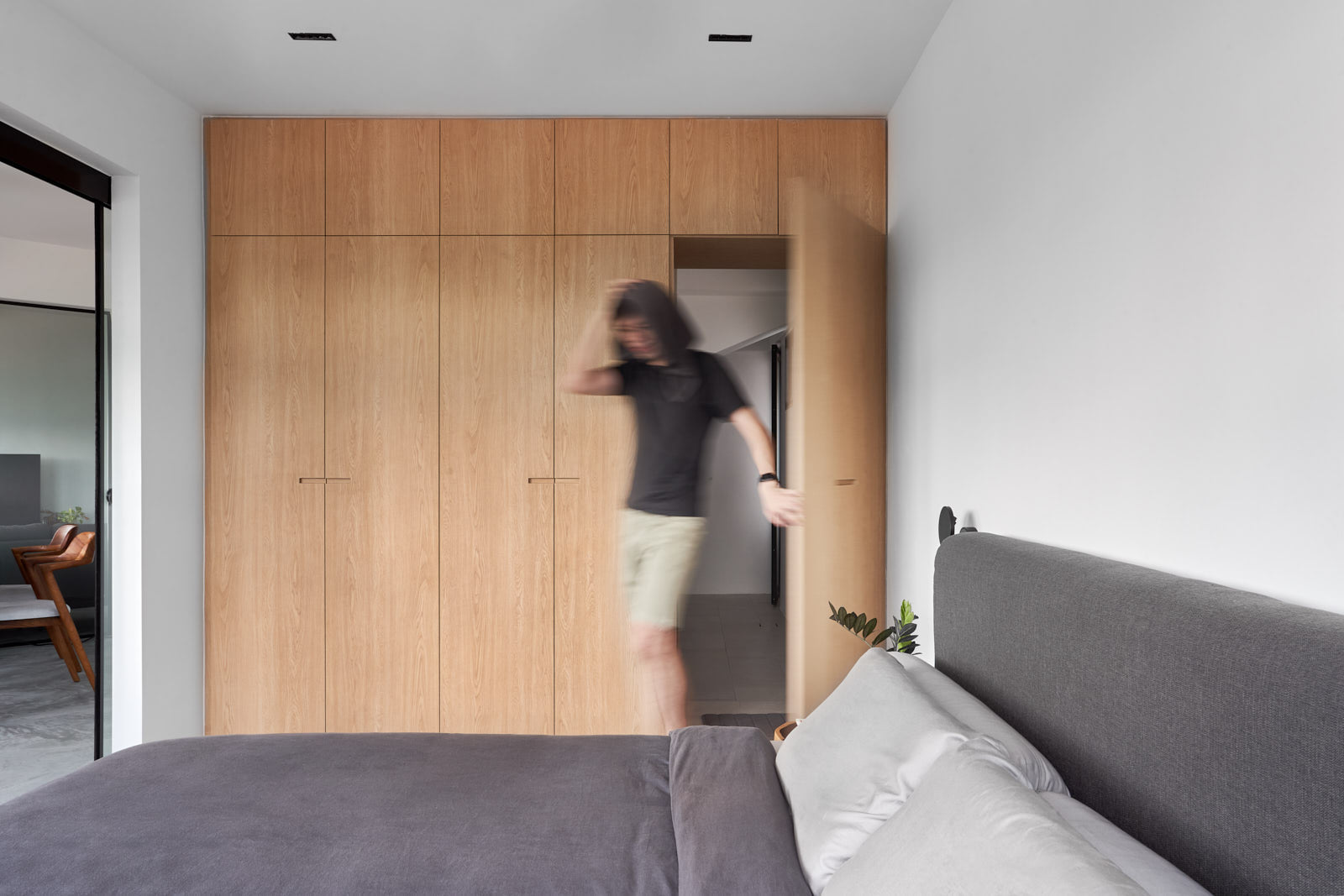 Simple bedroom: Our quiet sanctuary - Wooden wardrobe, modern interior, person entering, gray sofa, black chair, plant in