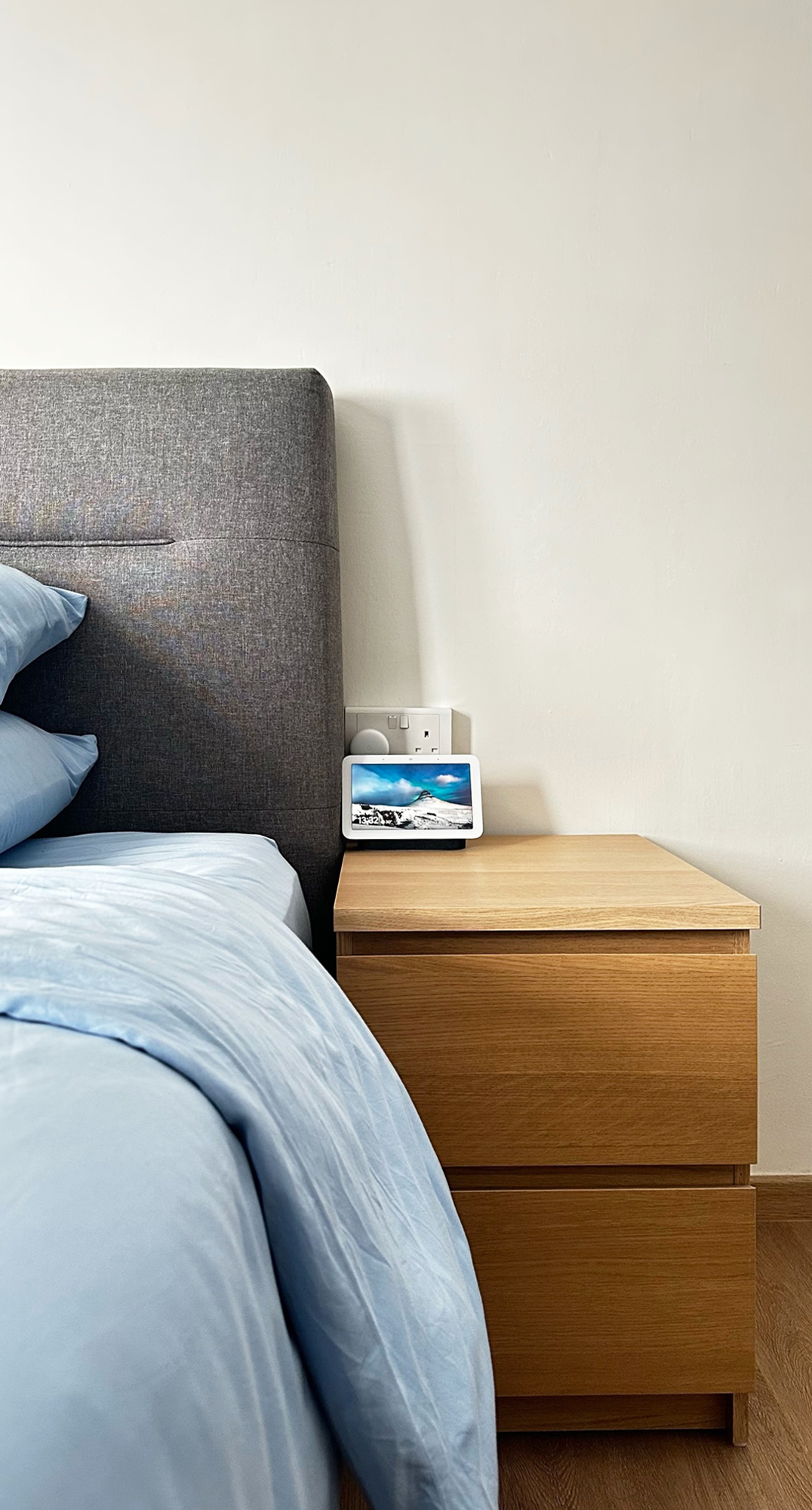 Our Bedroom, Our Sanctuary - Grey headboard, blue bedding, wooden nightstand, tablet on nightstand, white power outlet