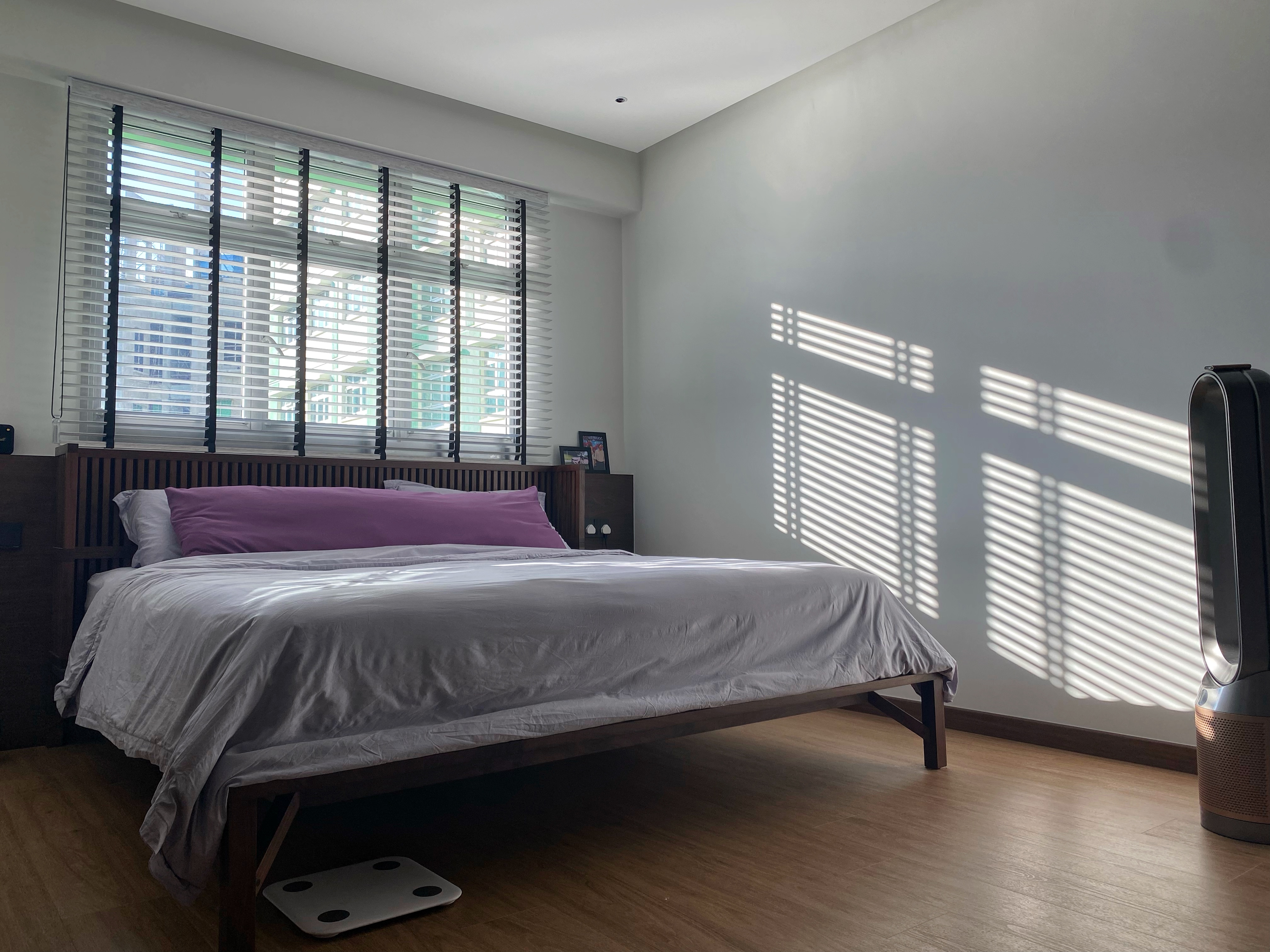 When sunlight hits, when darkness falls. - Modern bedroom with large window, white blinds casting shadows, neatly made bed