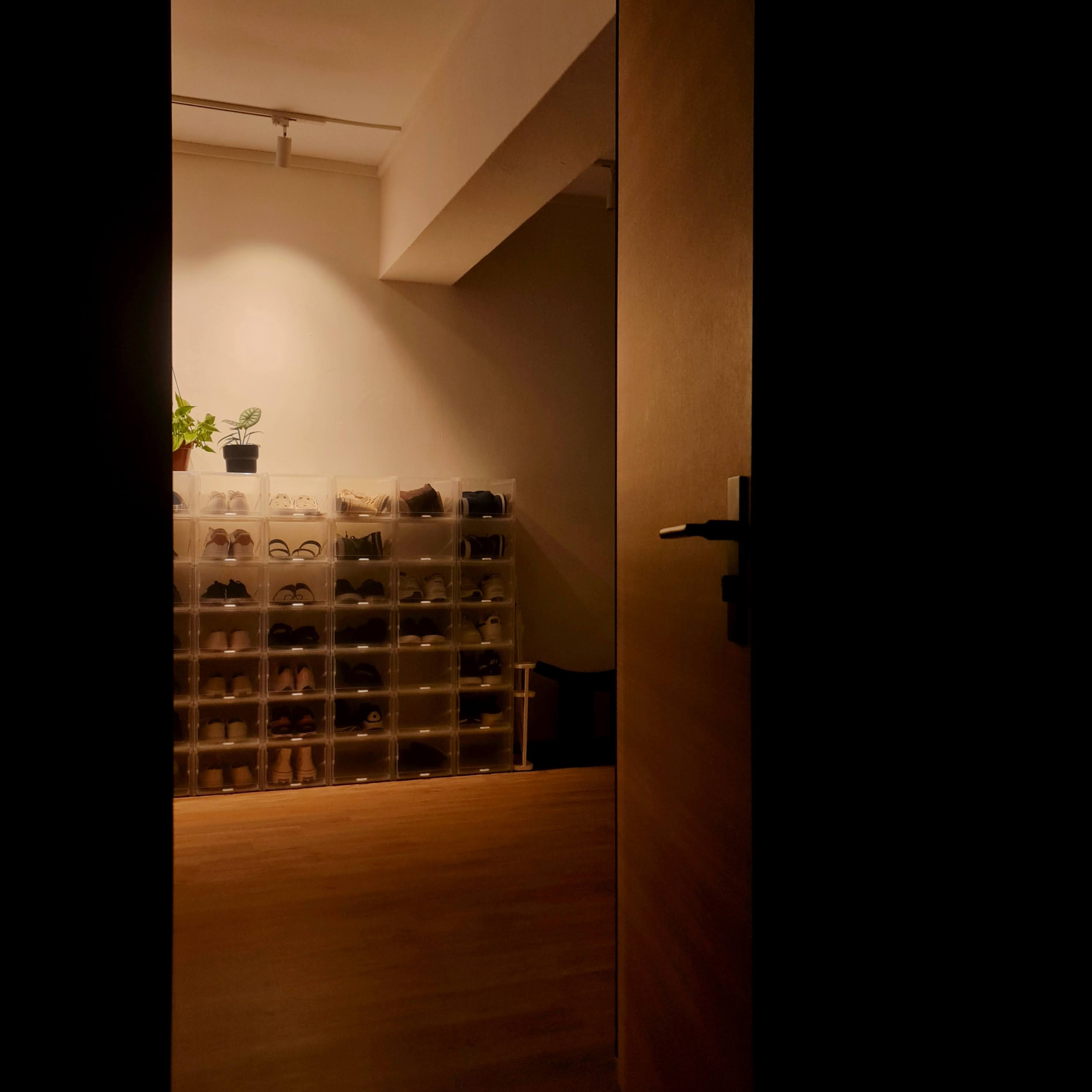 No more searching for our soles - Shelf with shoes, transparent storage bins, indoor lighting, wooden floor, dark doorway