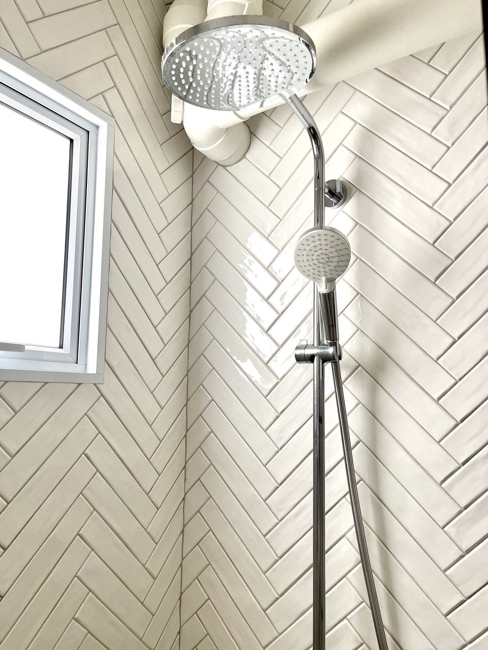 Our Private Sanctuary - Herringbone tile wall, modern showerhead, chrome fixtures, white herringbone pattern, window above