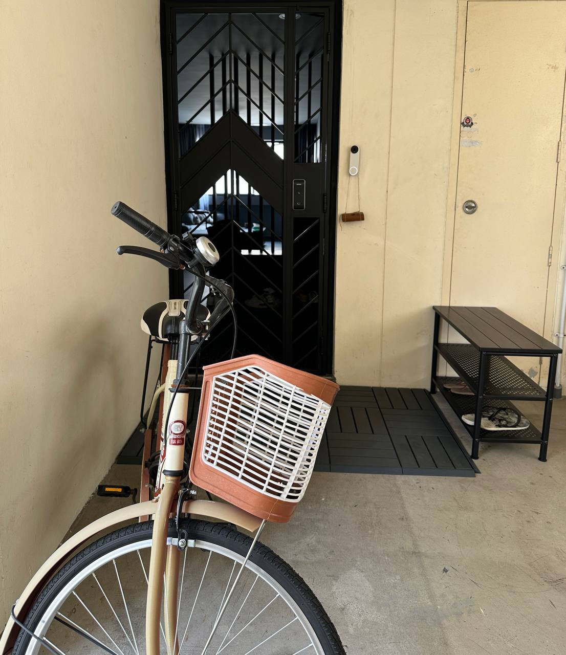 Stepping up our doorway game - Black bicycle with beige frame, brown basket, black metal gate, beige wall, black door, small