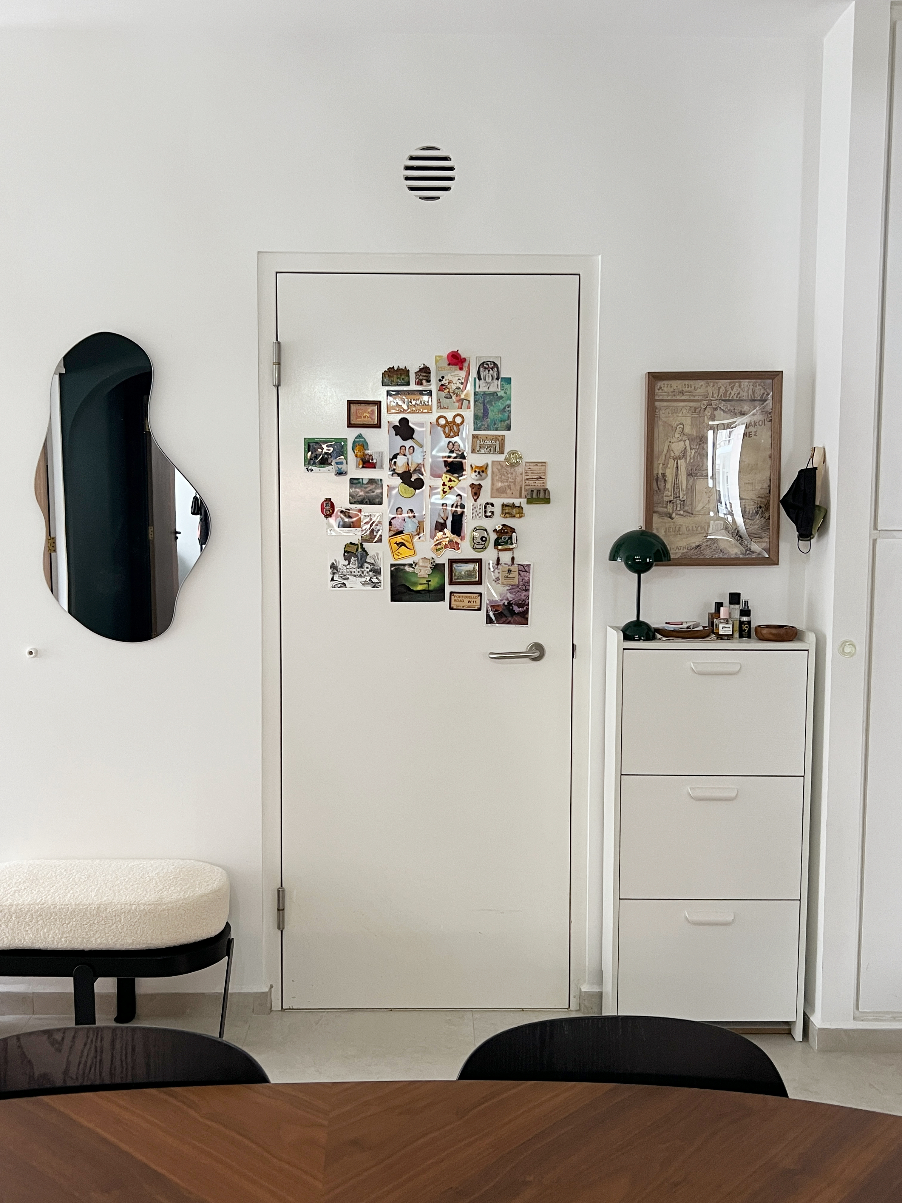 Our entryway of our 4 room BTO (No Carpentry) - White door adorned with various magnets, sleek modern mirror, minimalist