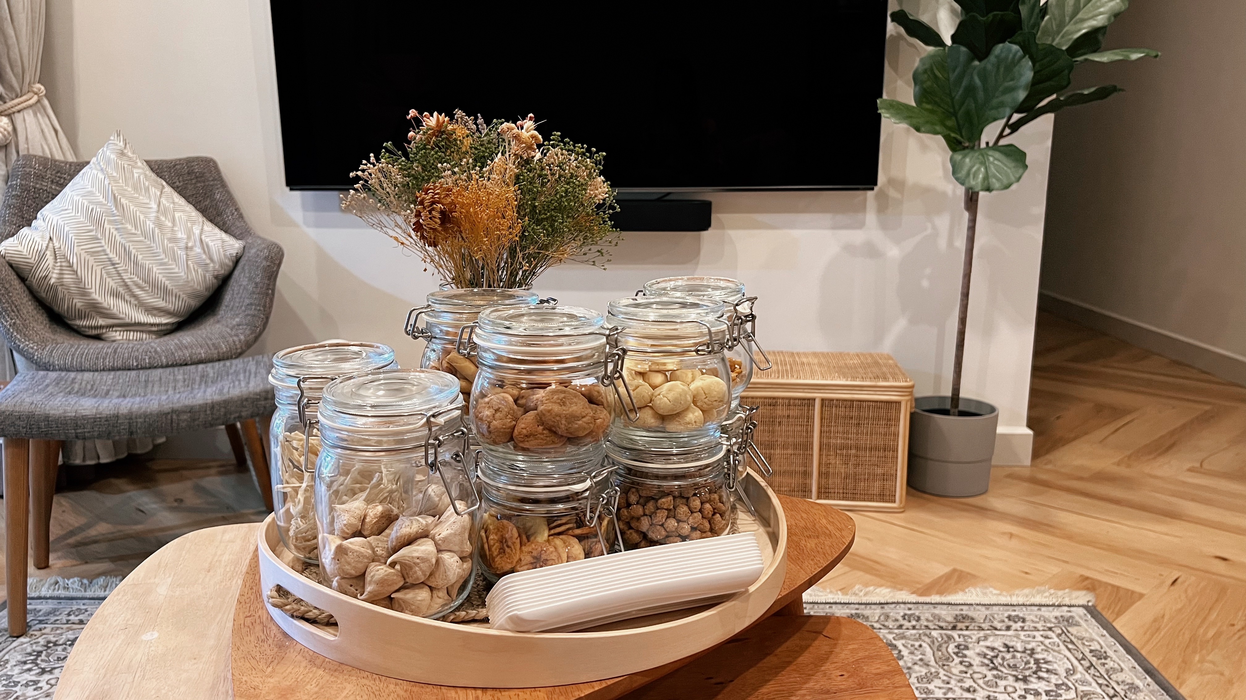 A living room refresh for Hari Raya! - Jars filled with nuts and dried fruits on wooden tray, gray armchair with patterned