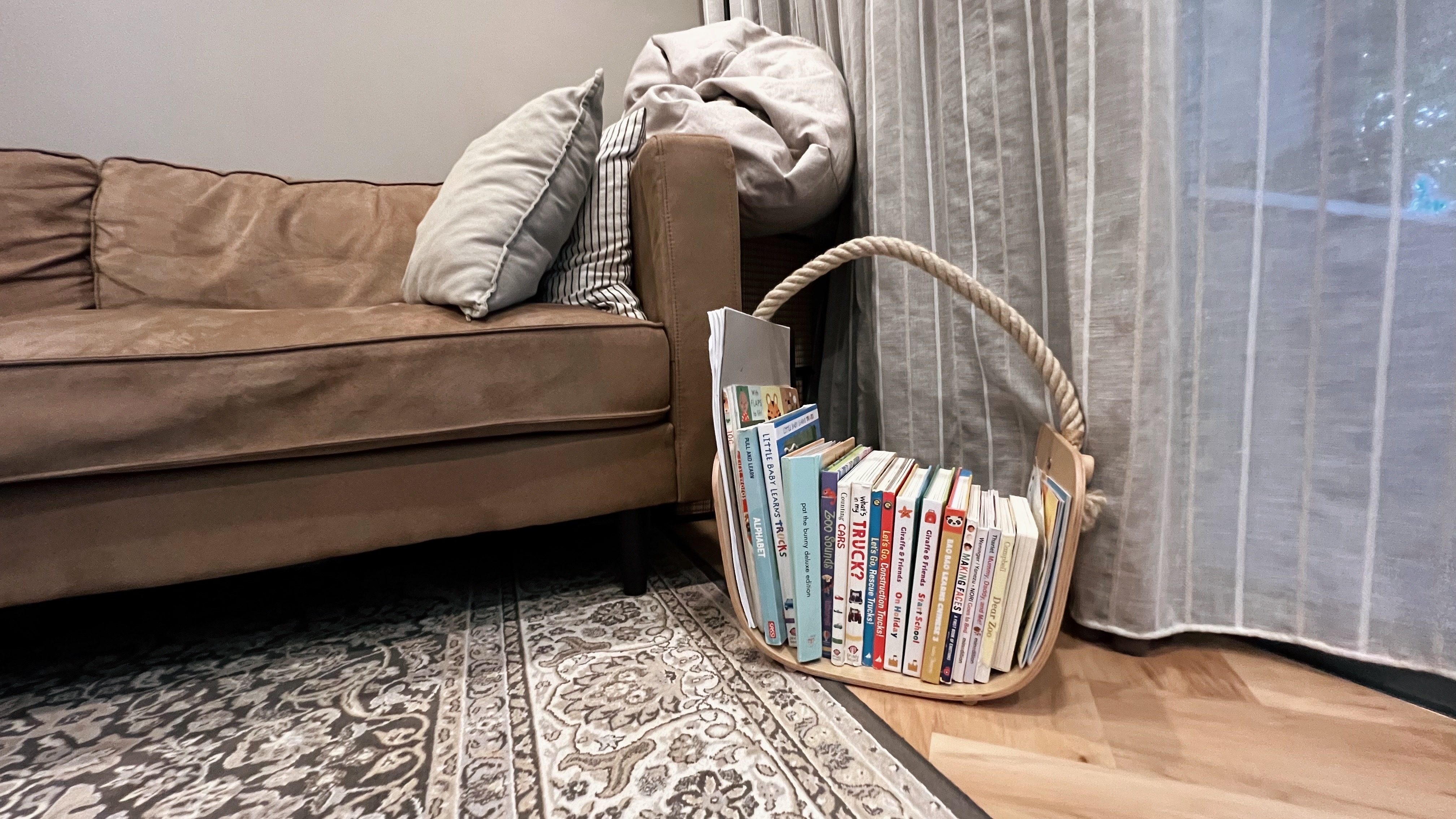 A living room refresh for Hari Raya! - Brown sofa, beige pillows, striped pillow, gray blanket, wooden basket, bookshelf