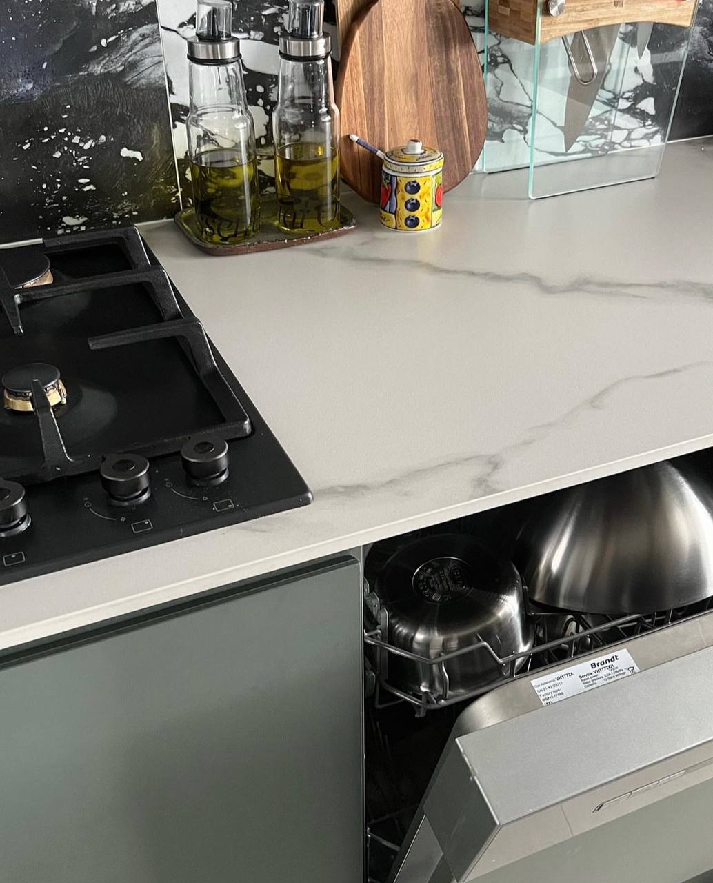 Where the wife spends most of her time at (her love for cooking). - glass bottle, olive oil, kitchen countertop, modern