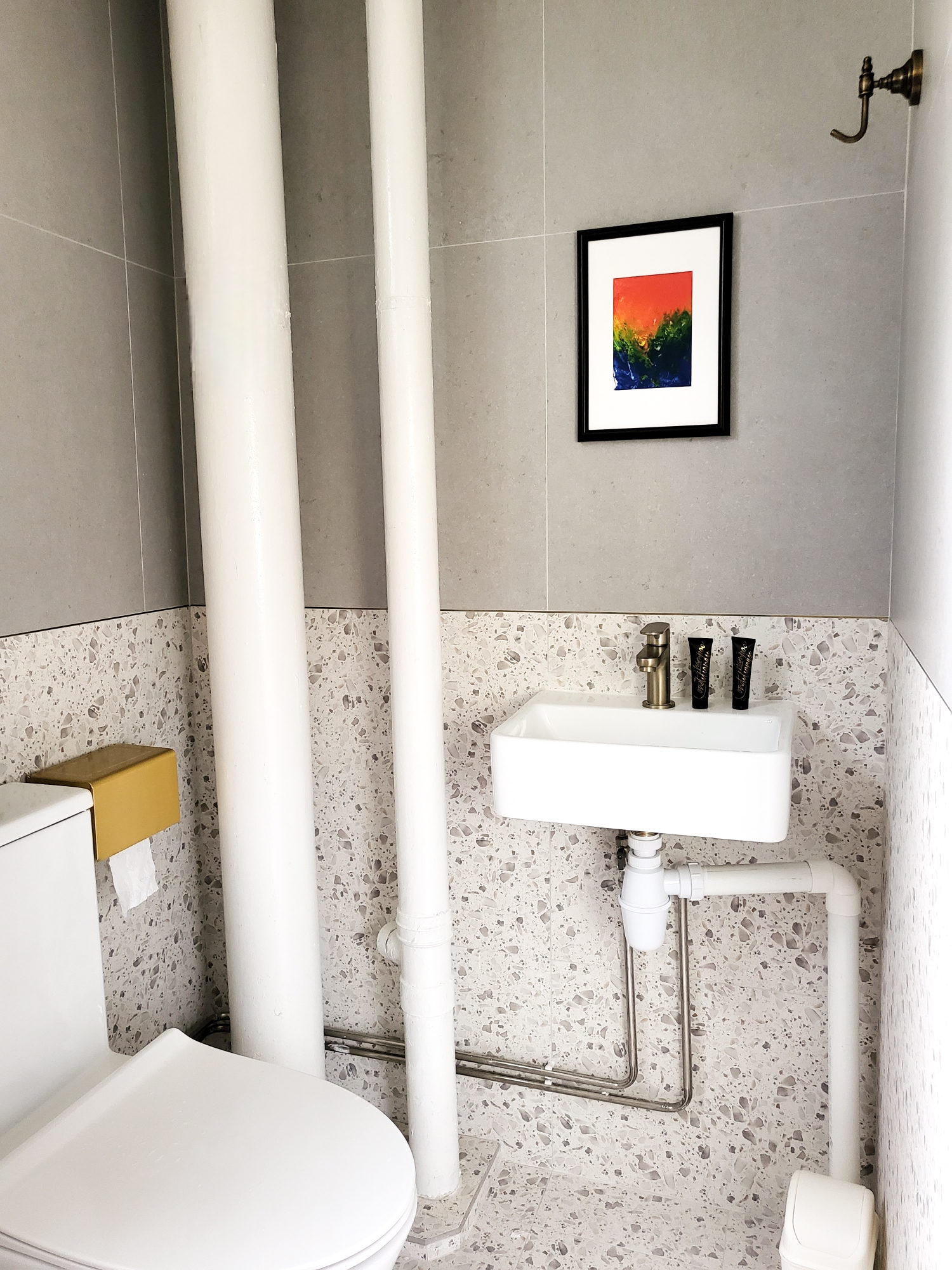 Spa-like Sanctuary right in your Bathroom  - White bathroom with modern fixtures, gray tiled walls, framed artwork, white