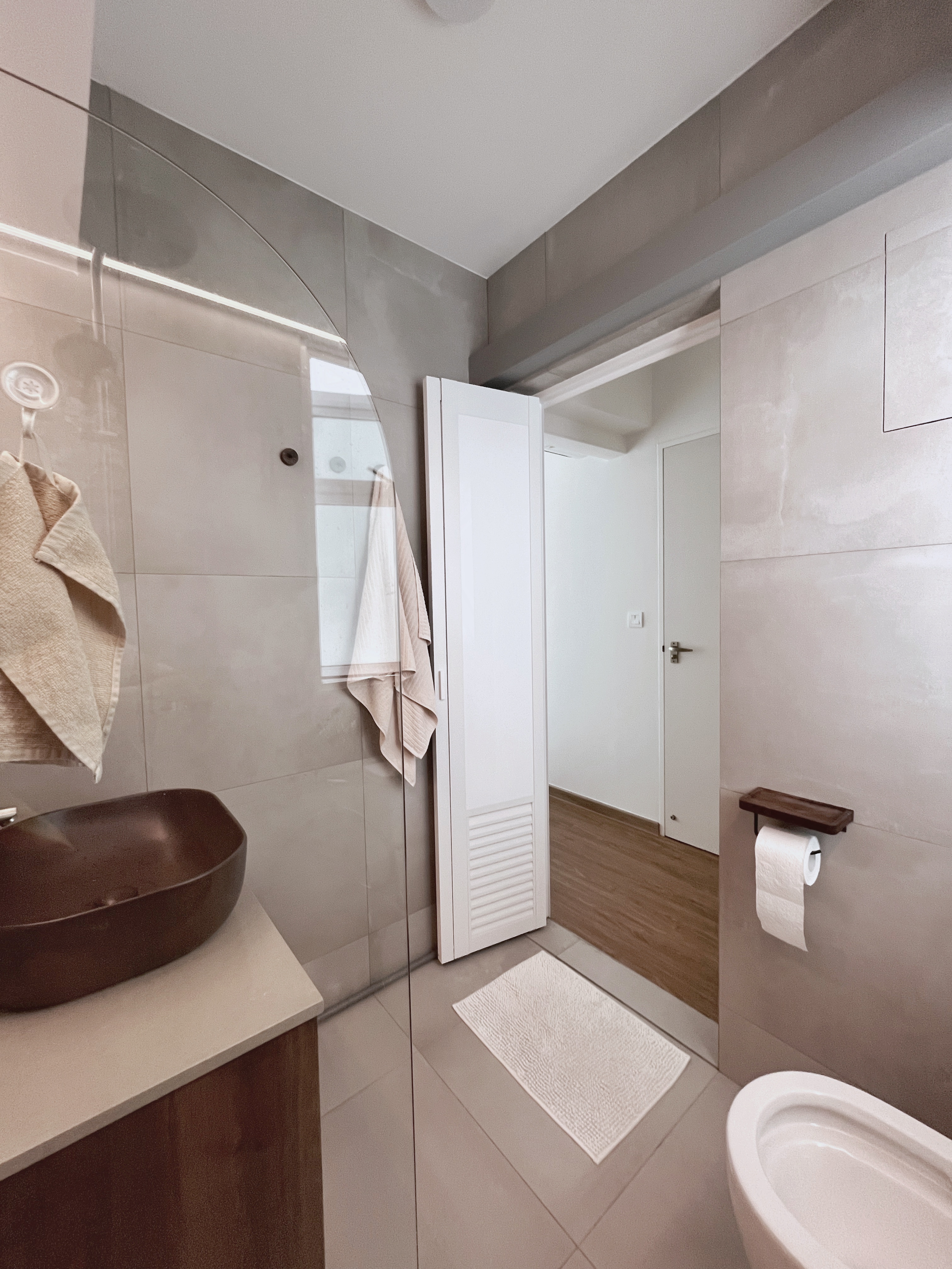 12 Bathroom Renovation Tips We Learned - Modern minimalist bathroom, beige towels, sleek design, large mirror, glass shower