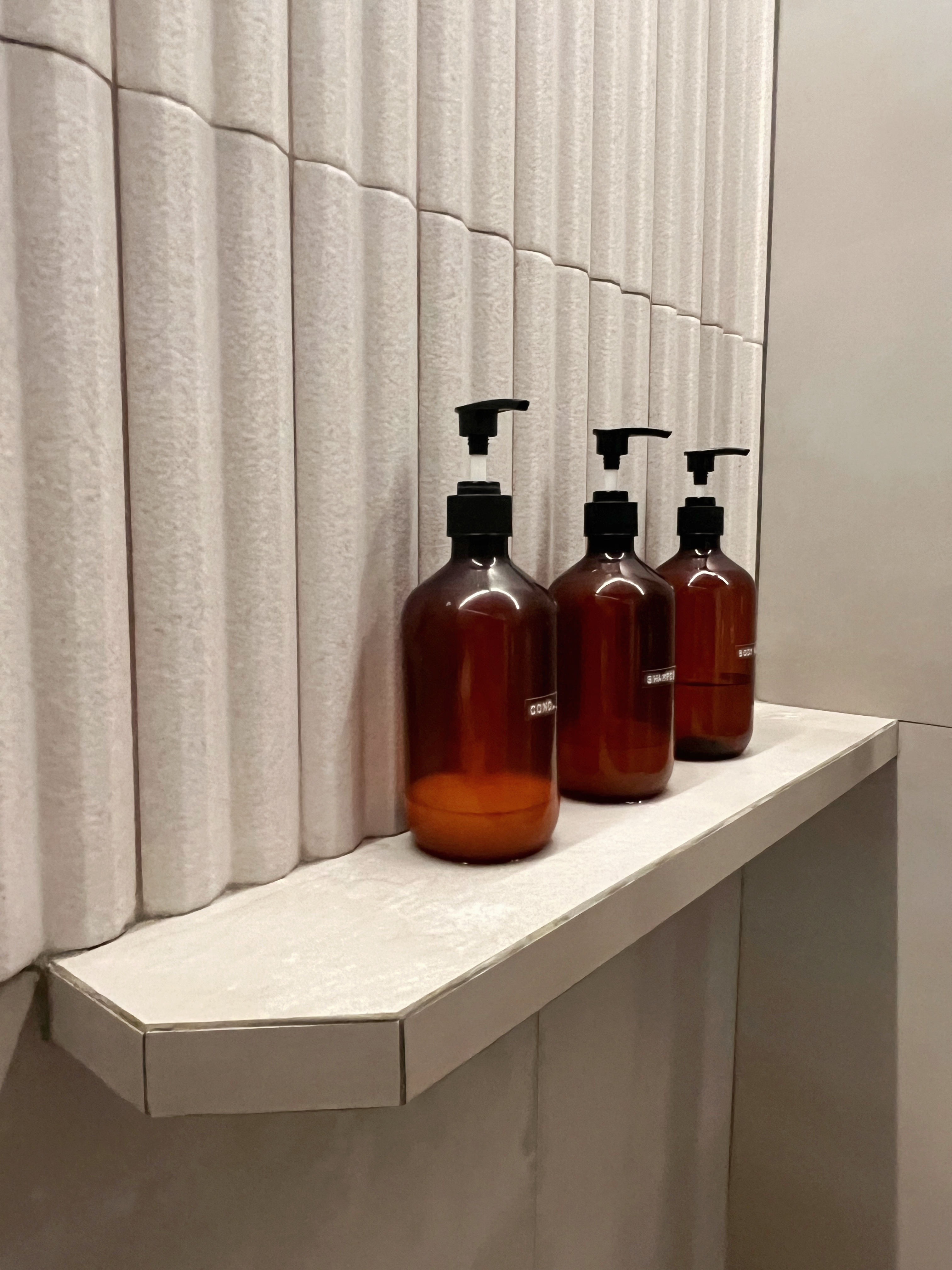 12 Bathroom Renovation Tips We Learned - Brown soap bottles, sleek design, modern bathroom, wall-mounted shelves, minimalist