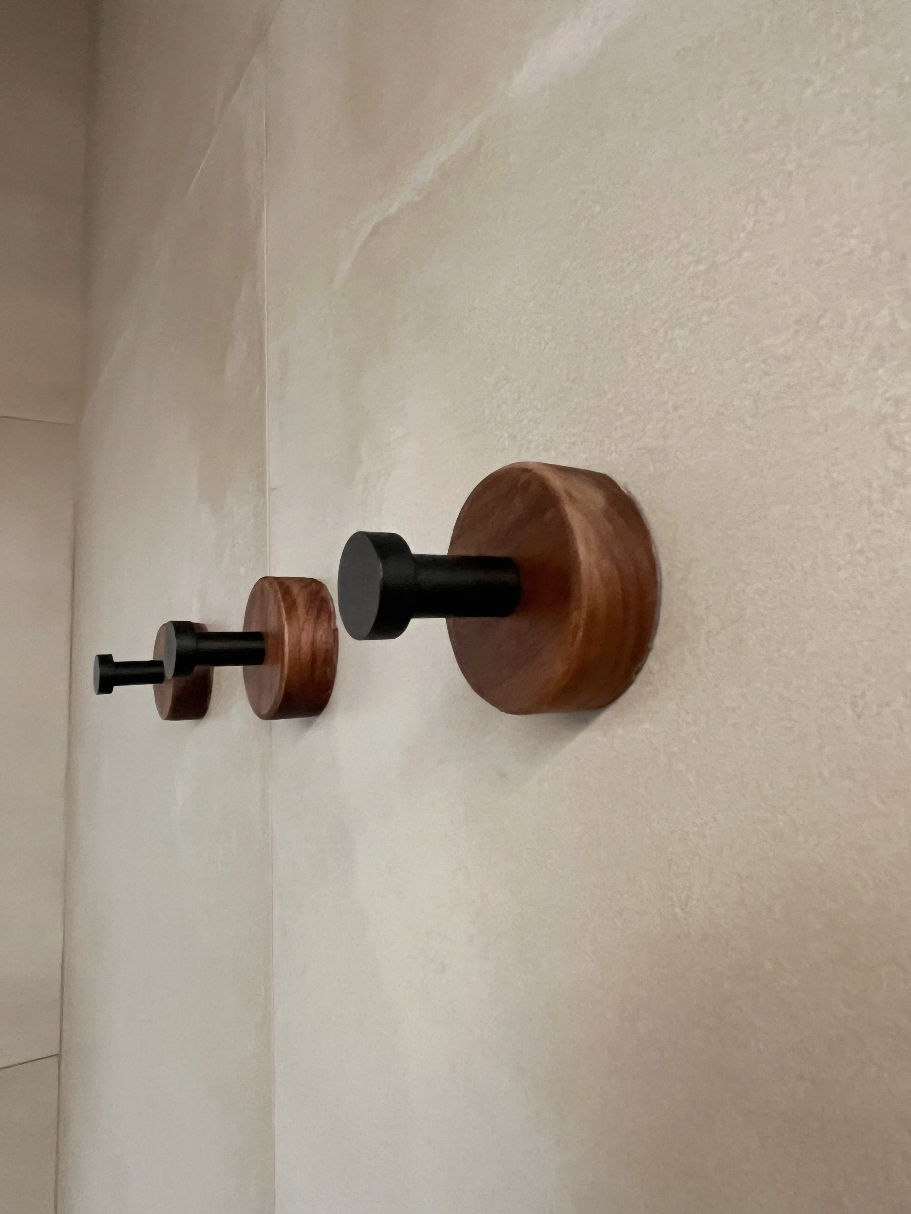 12 Bathroom Renovation Tips We Learned - Wooden wall hangers, minimalist design, natural wood finish, black knobs, textured