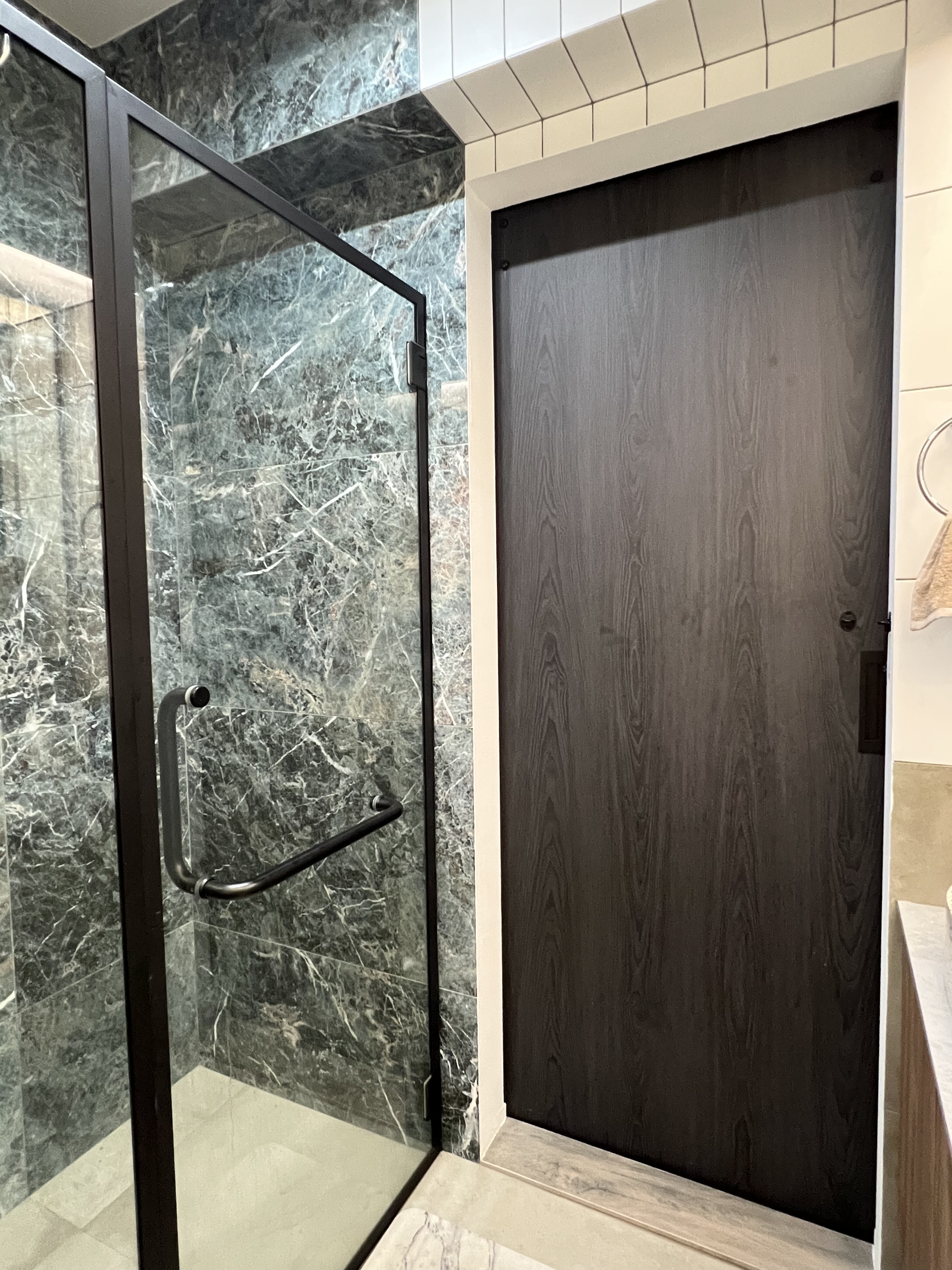 Hotel Inspired Master Bathroom Toilet  - Glass shower enclosure, marble walls, black metal frame, glass door, wooden door