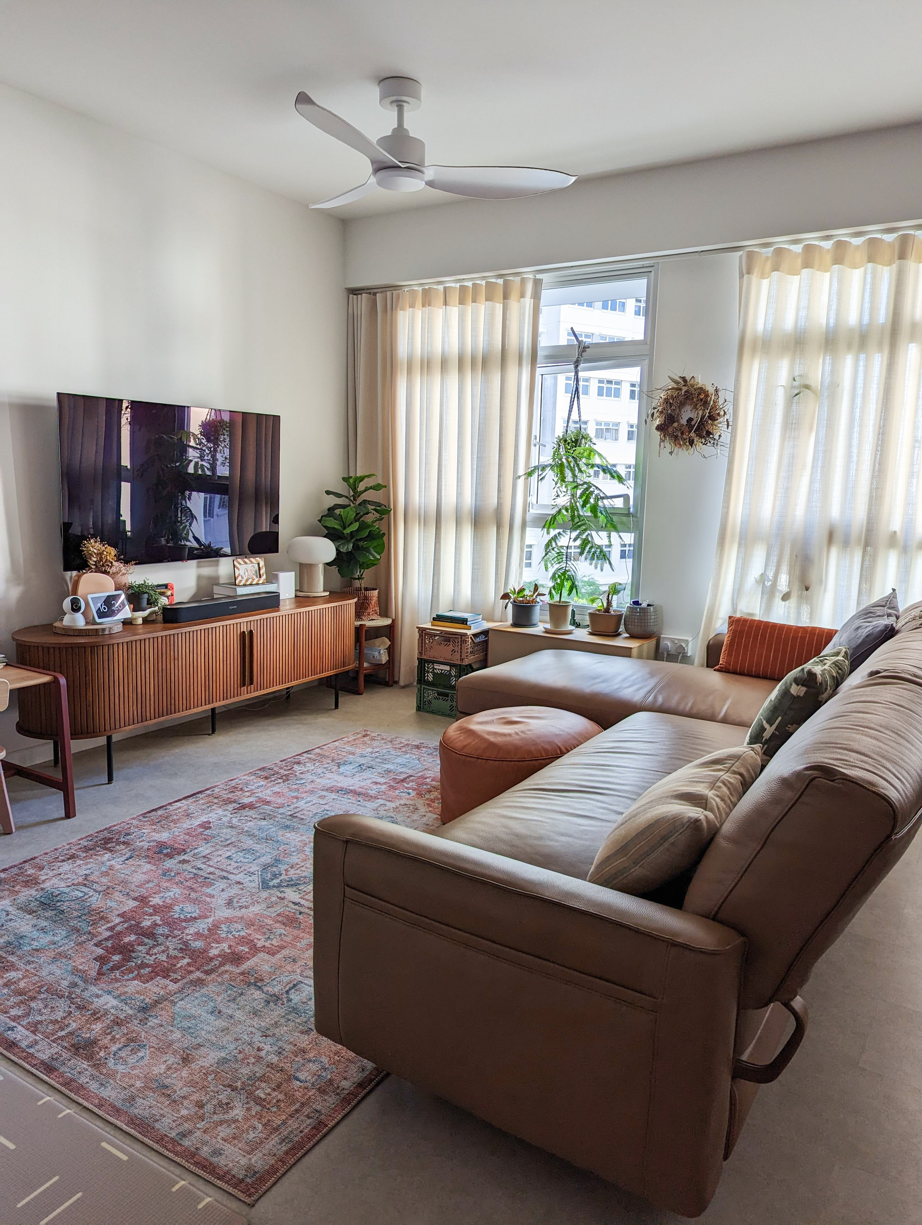 Living Space | More space, more life - Modern living room with large flat-screen TV, beige curtains, brown leather sofa