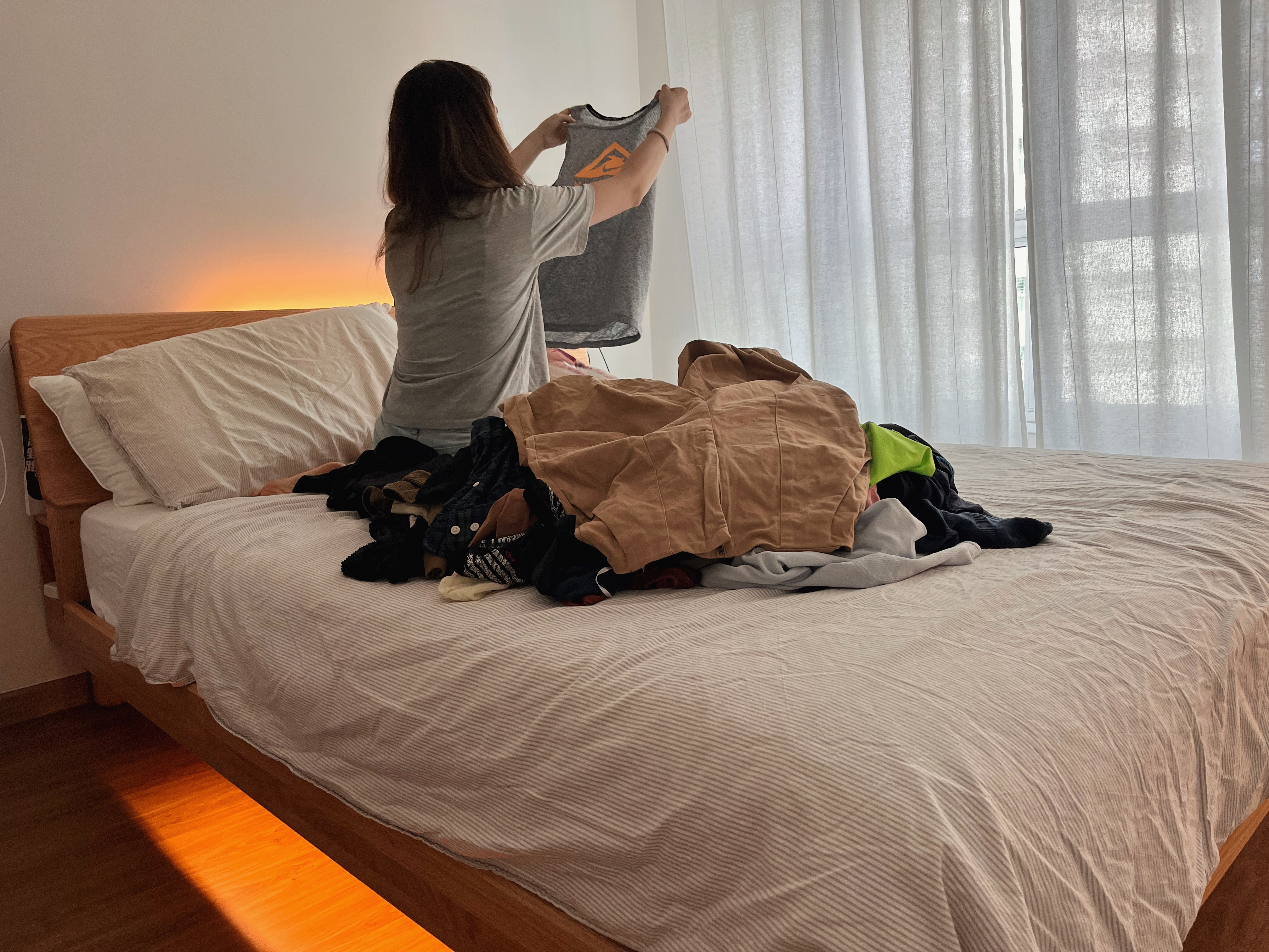 Light, Scent, Sound for the Ultimate Cosy-trinity - Gray shirt, person, holding shirt, room, bed, clothes, morning light