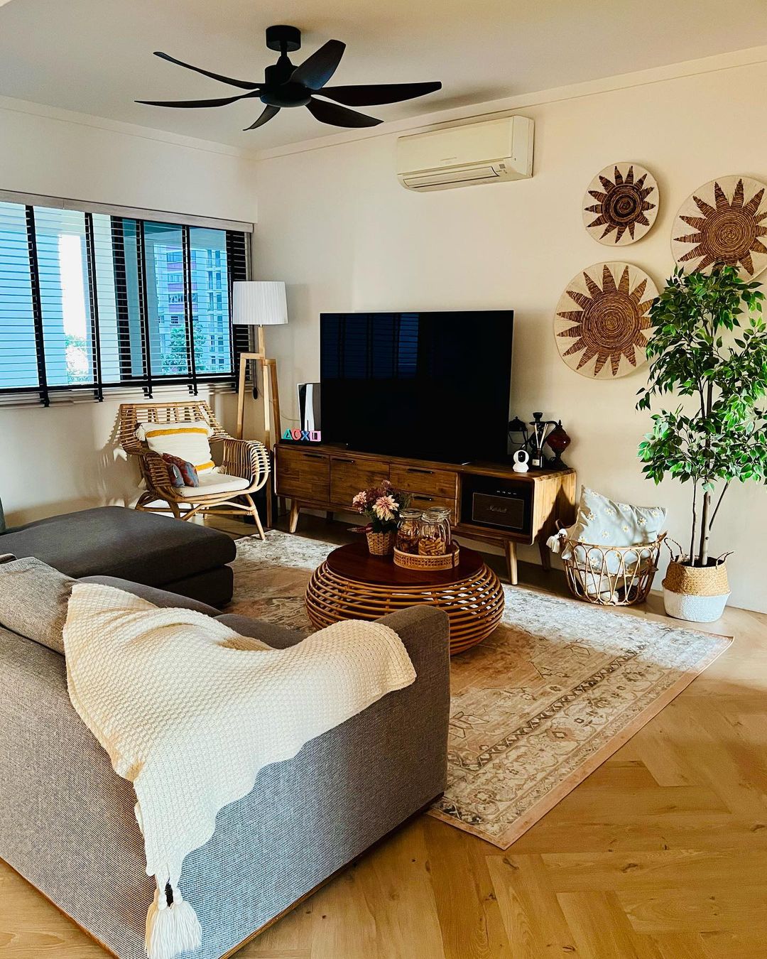 Scandinavian living room infused with Bali vibes 🏝🏖⛱ - Modern living room with large window, sunburst wall art, wooden