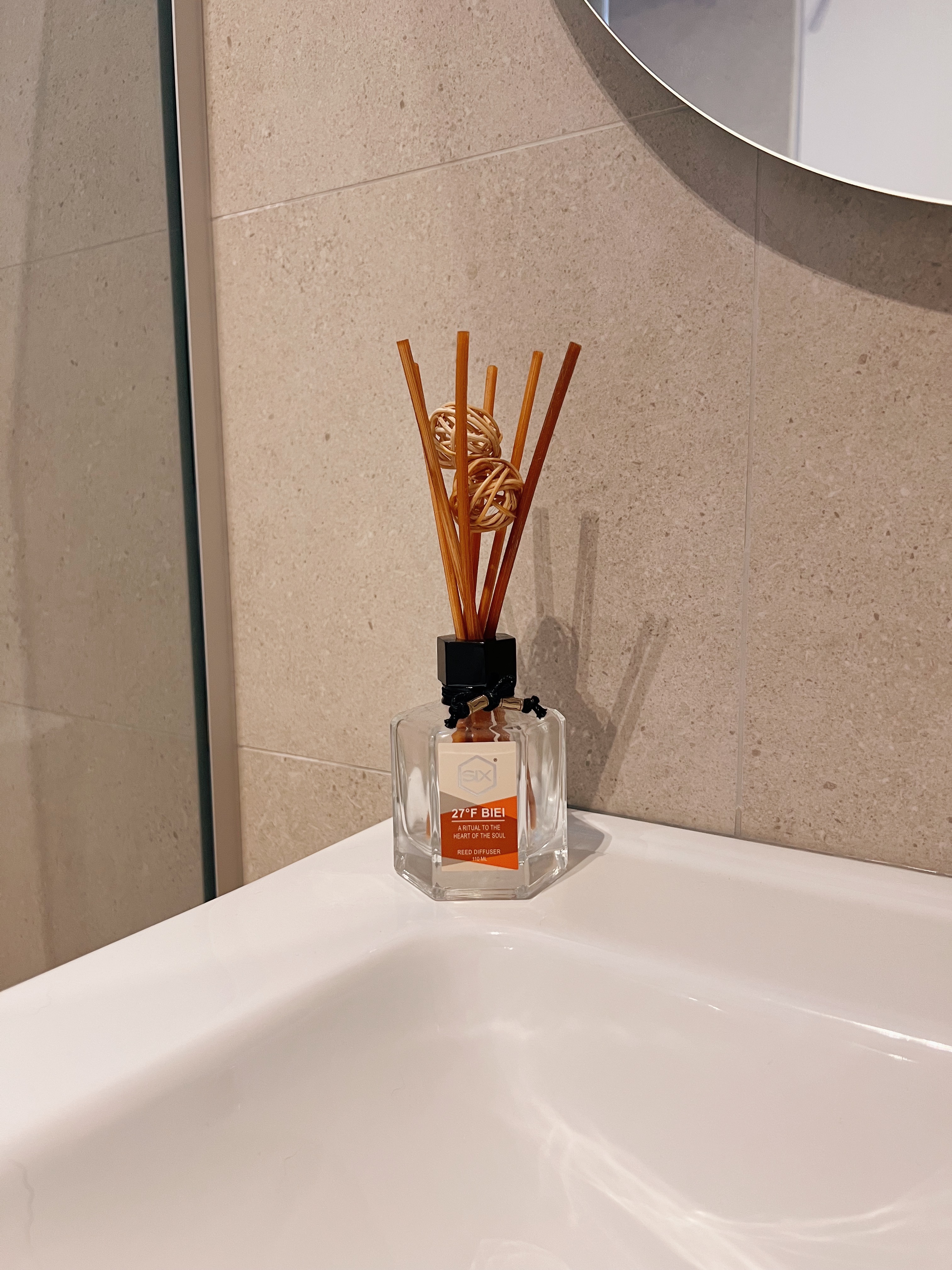 Entering a state of relaxation in our bathrooms - Bathroom setting, clear glass bottle, wooden sticks, diffuser, natural