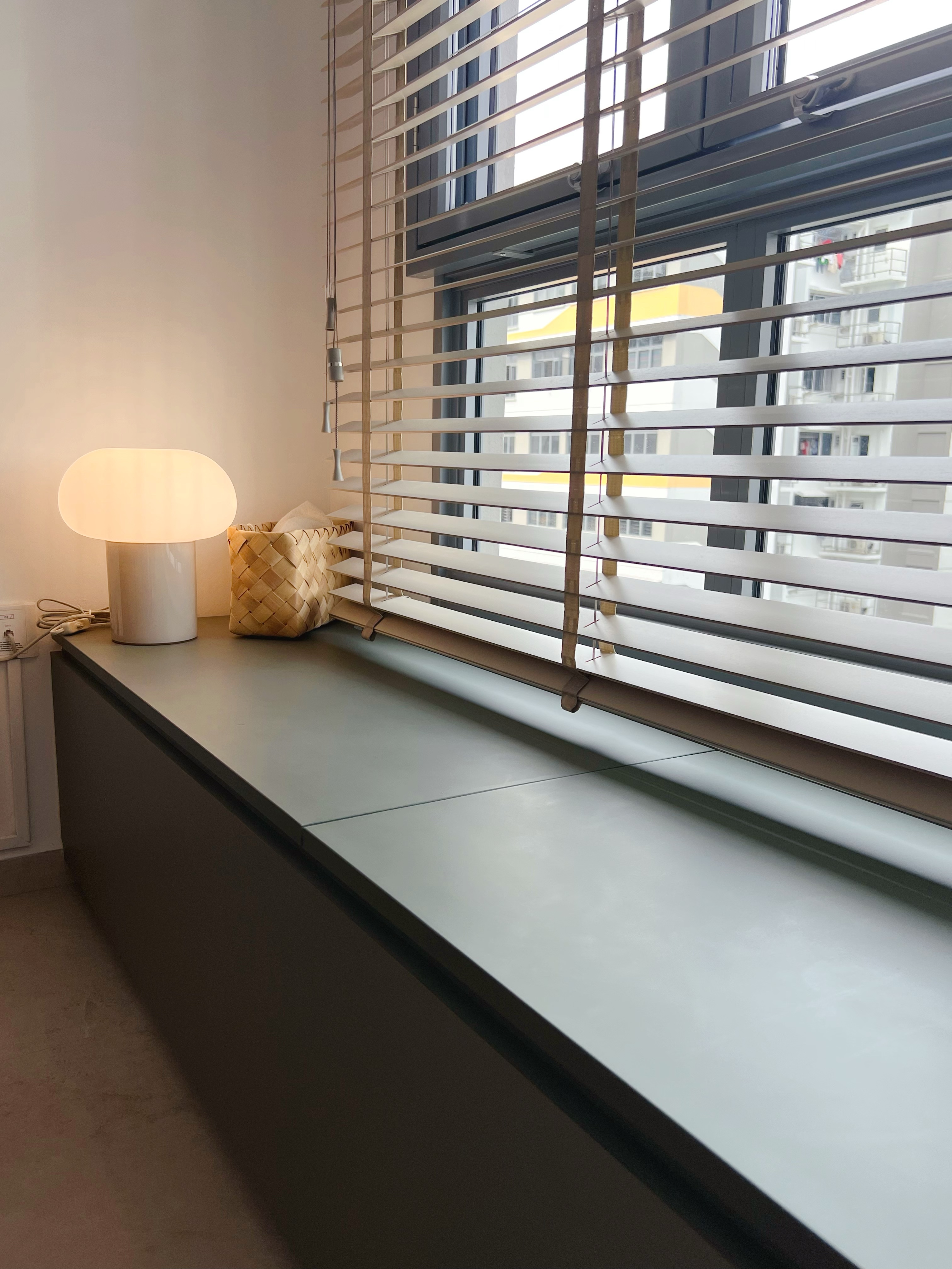 Our Simple but Cozy Living Room  - Modern minimalist interior, soft lighting, window with blinds, white lamp with soft glow