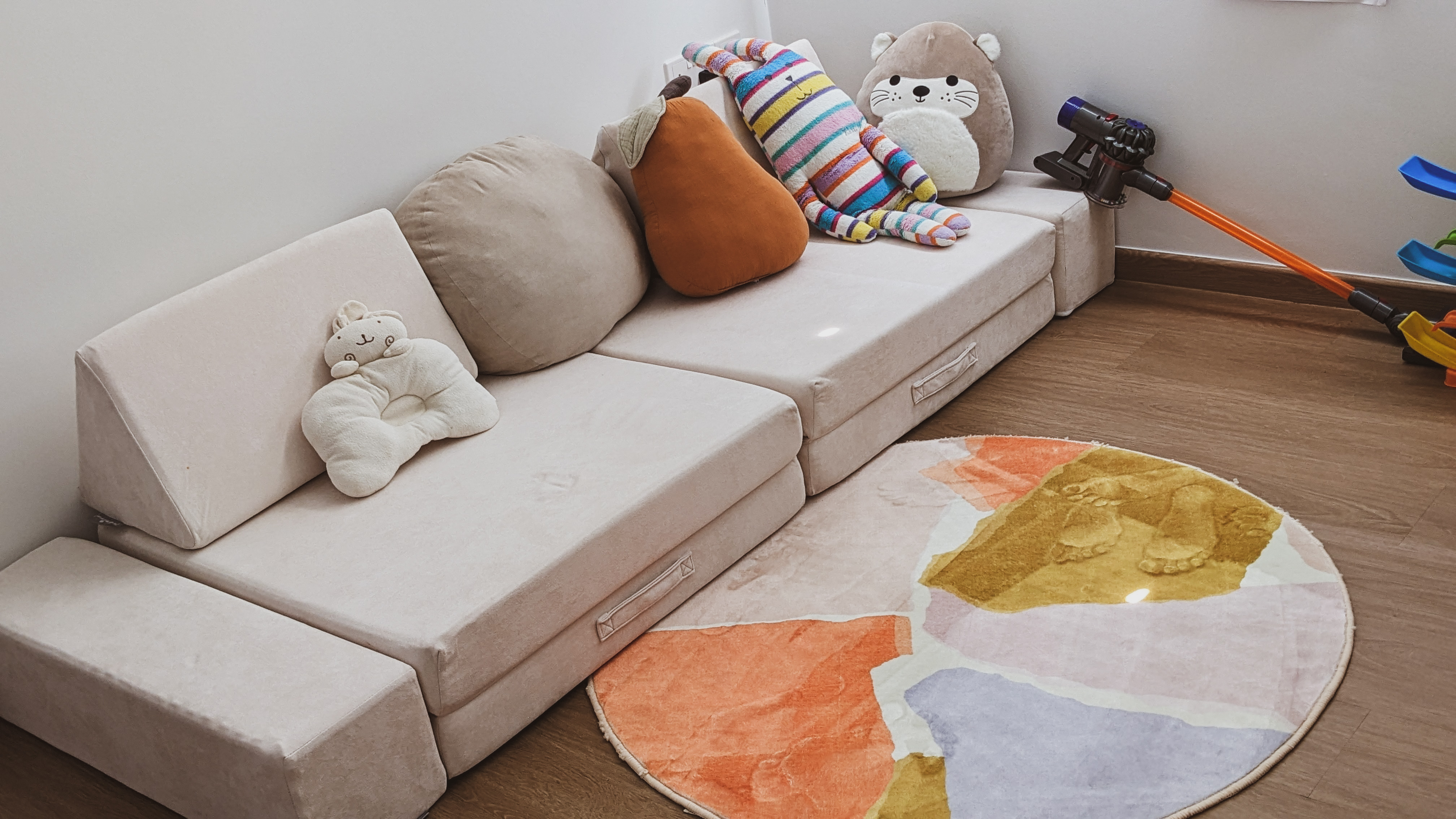Child's Play | Flourish. Create. Connect. - Soft, beige sofa with plush toys, including teddy bear and striped plush