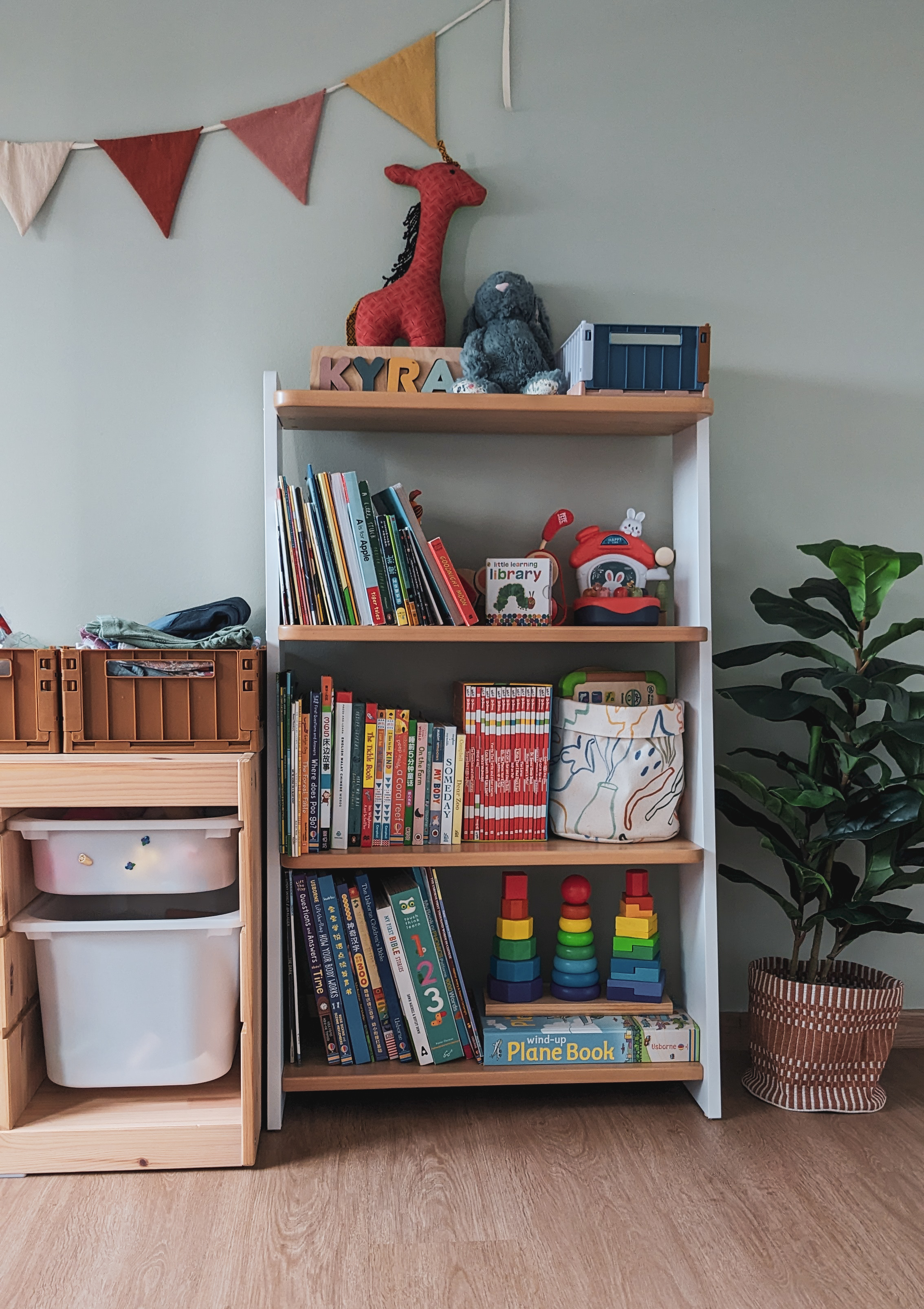 Child's Play | Flourish. Create. Connect. - Wooden bookshelf, colorful triangular flags, red giraffe toy, blue toy train