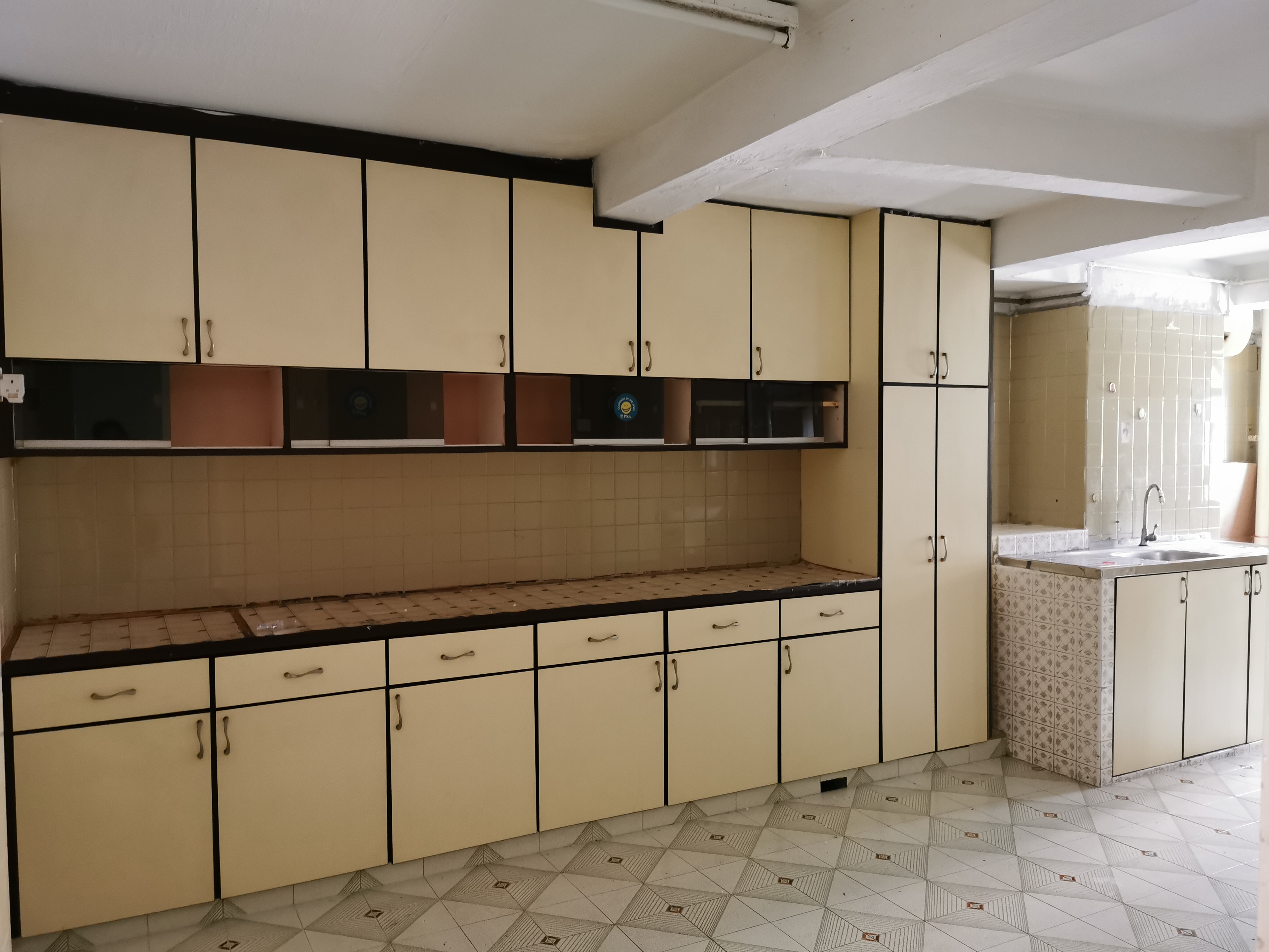 Transforming a 1980s wall kitchen - Cream-colored kitchen cabinets with black handles, tiled backsplash, empty countertop