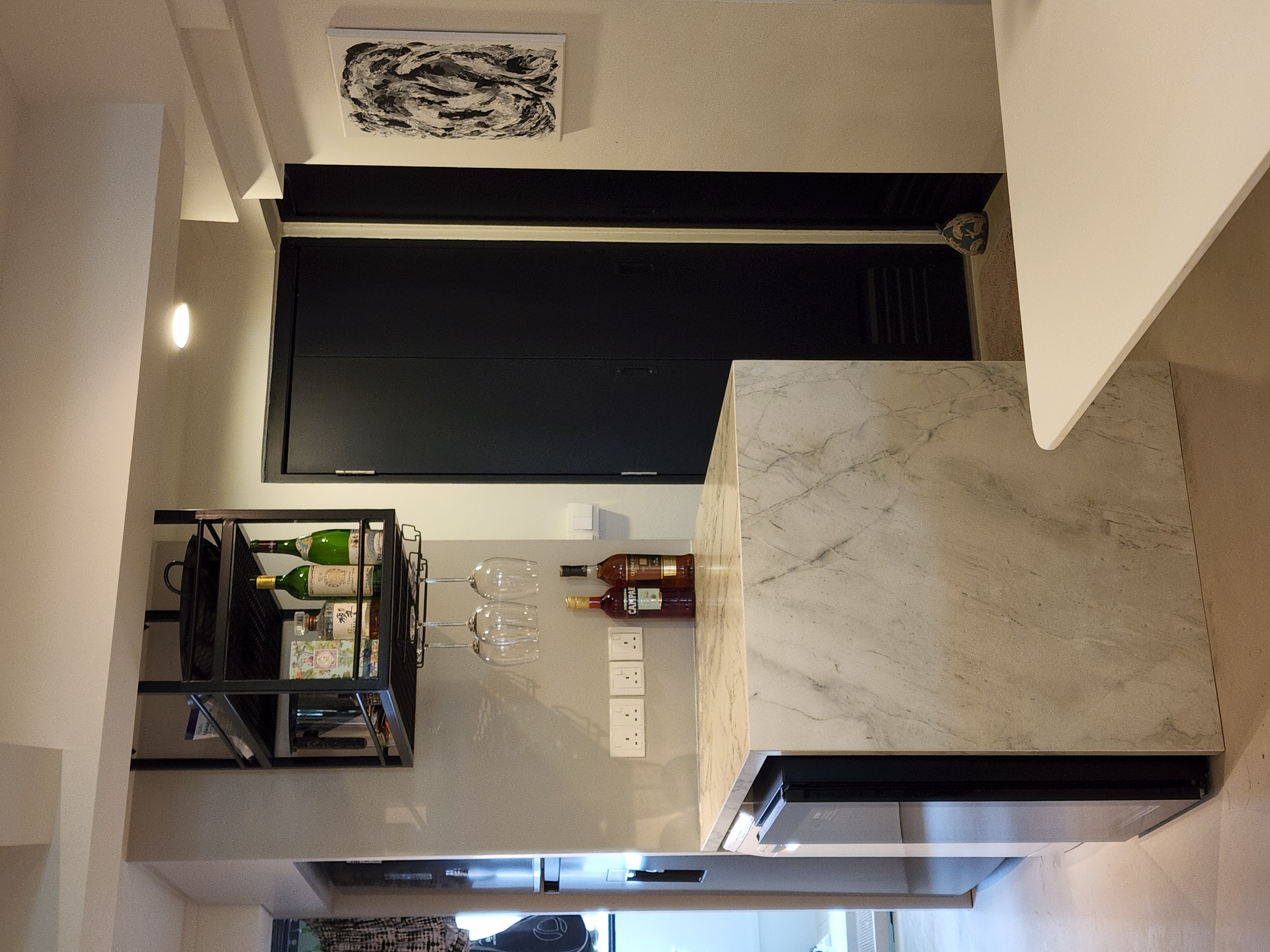 Transforming a 1980s wall kitchen - modern kitchen, marble island, black cabinets, wine rack, clear glasses, wooden bottles