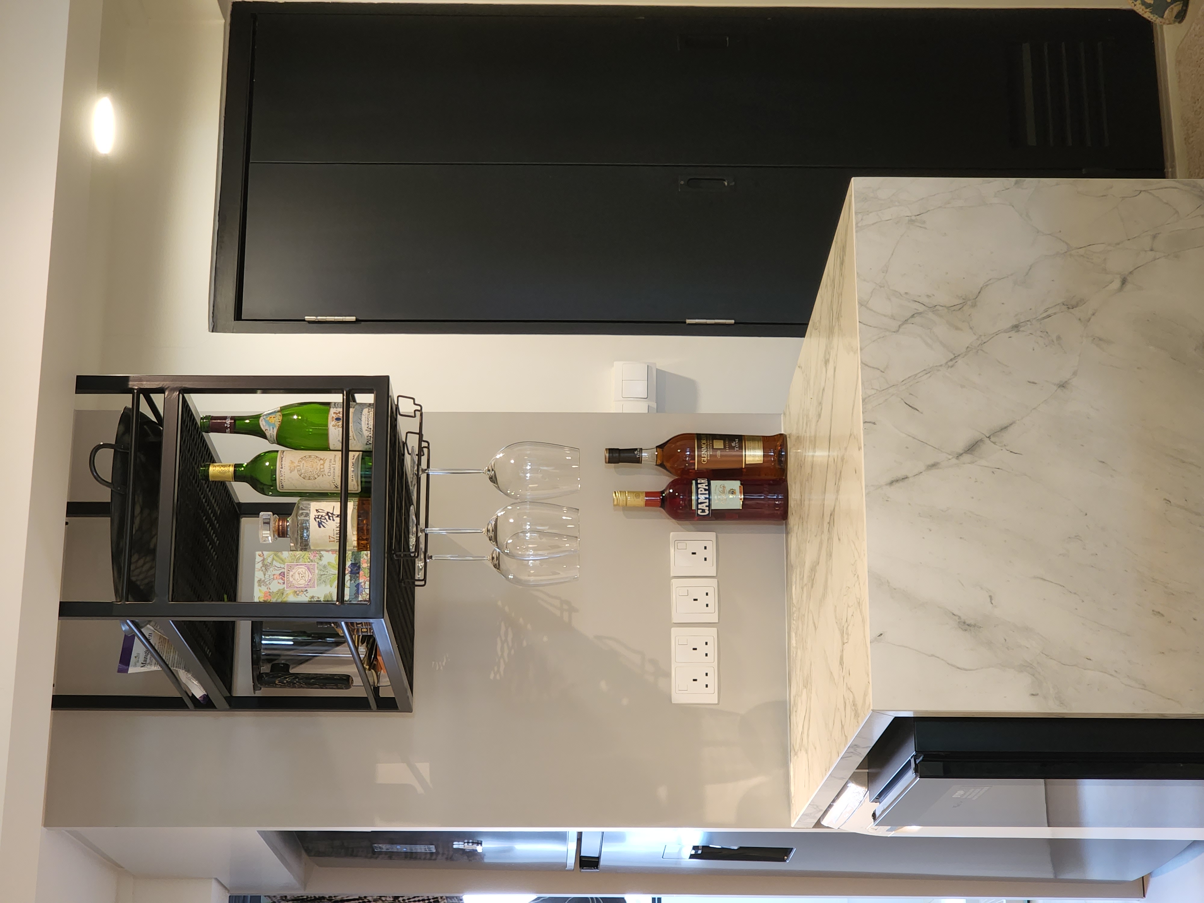 Transforming a 1980s wall kitchen - modern kitchen, marble countertop, wine rack, clear glasses, black shelving, wine