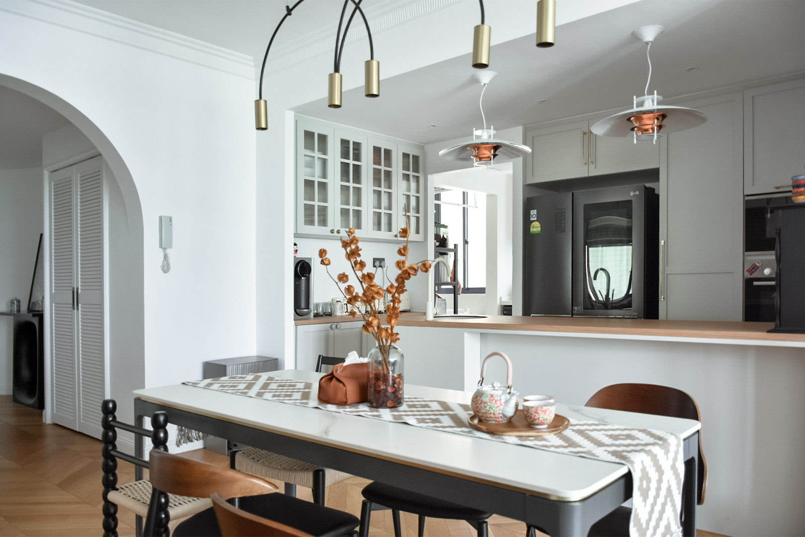 Gather - Dine  - Delight - Modern kitchen with white cabinets, pendant lights with gold accents, wooden floor, dining table