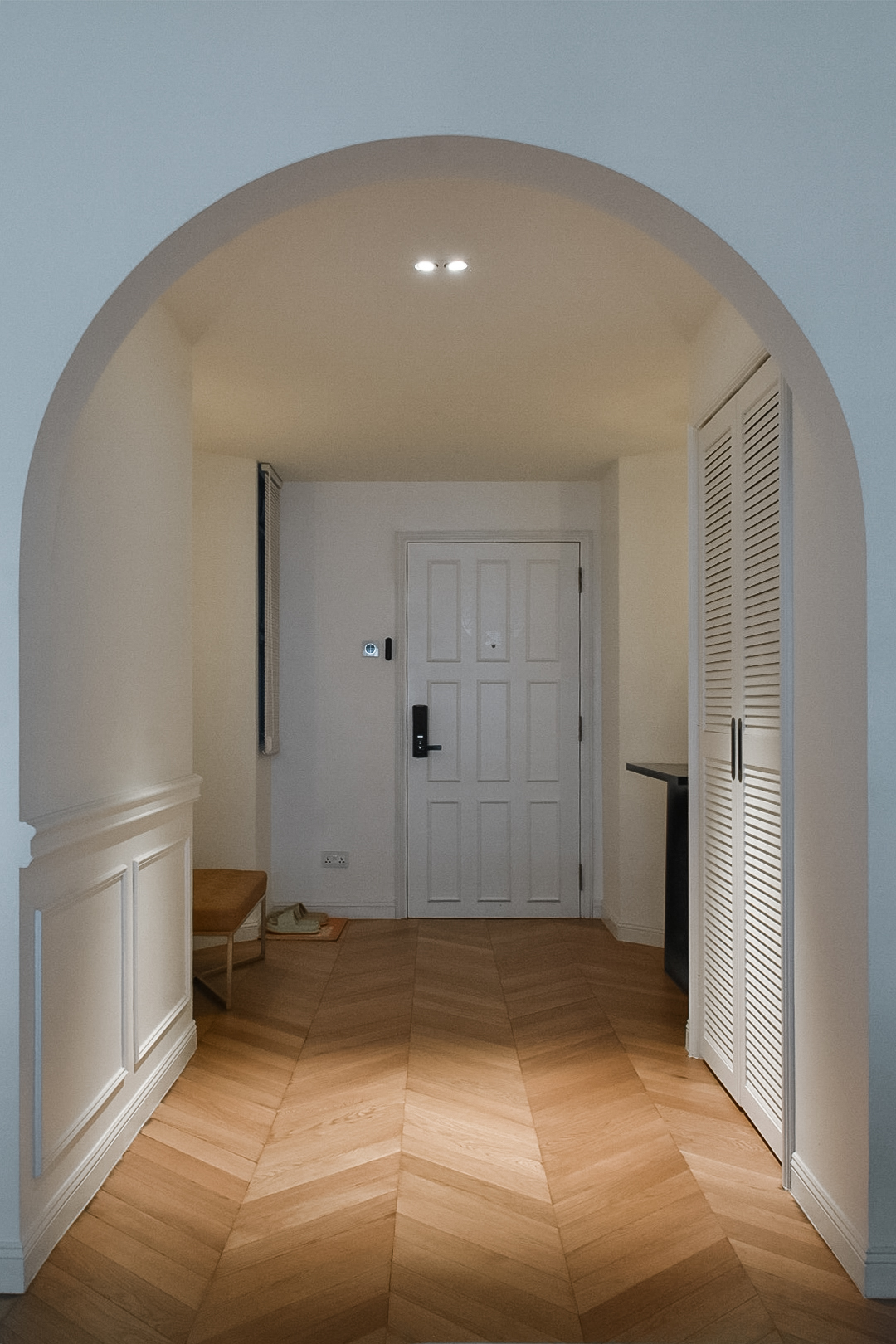 Archway Ambiance: Elevating Your Entry with Timeless Design - Herringbone wooden floor, arched hallway, white door, recessed