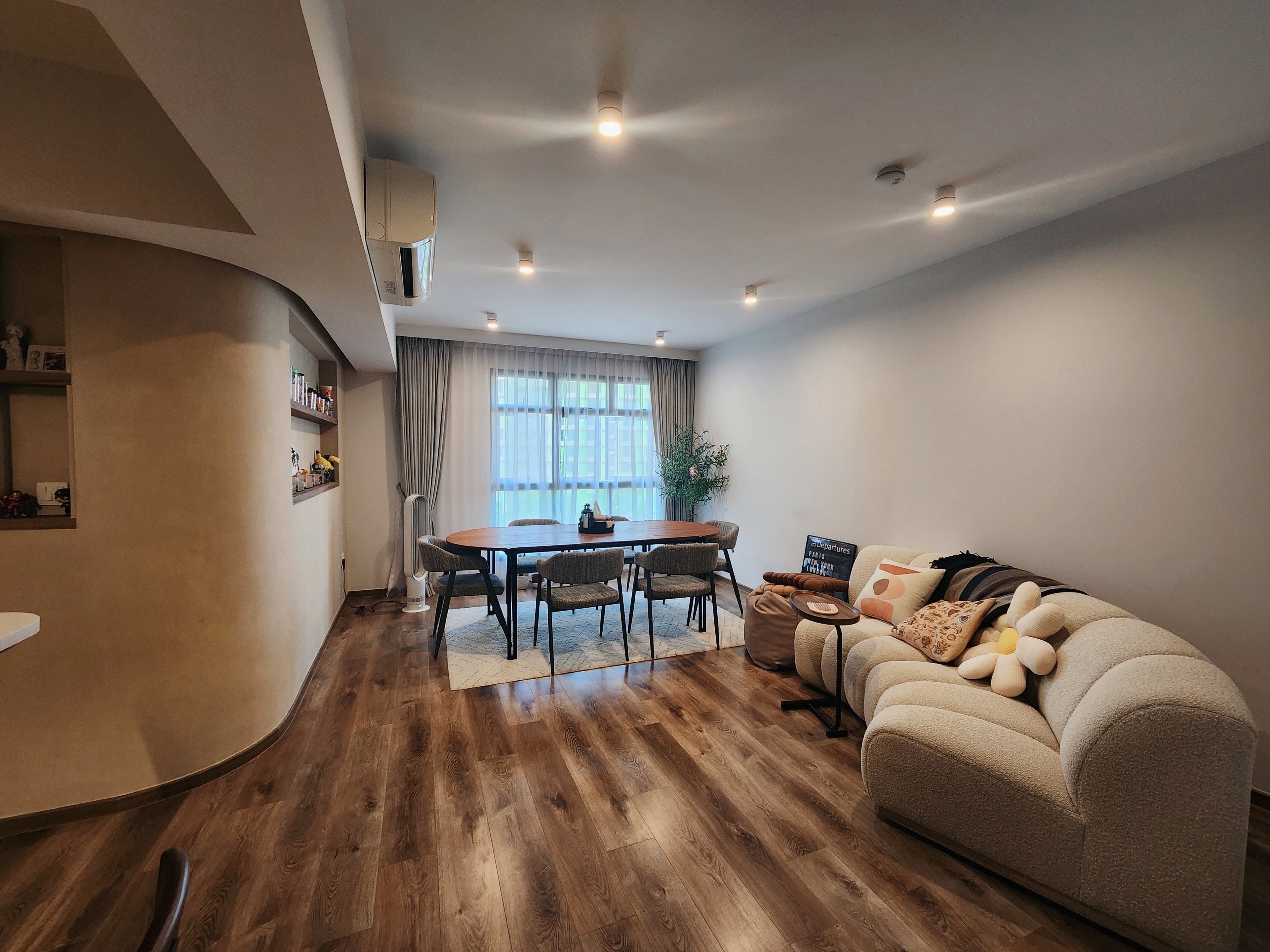 4 Room Warm, Curvy Contemporary Abode | Reno under $53k  - Modern living room with wooden flooring, beige walls, and a large