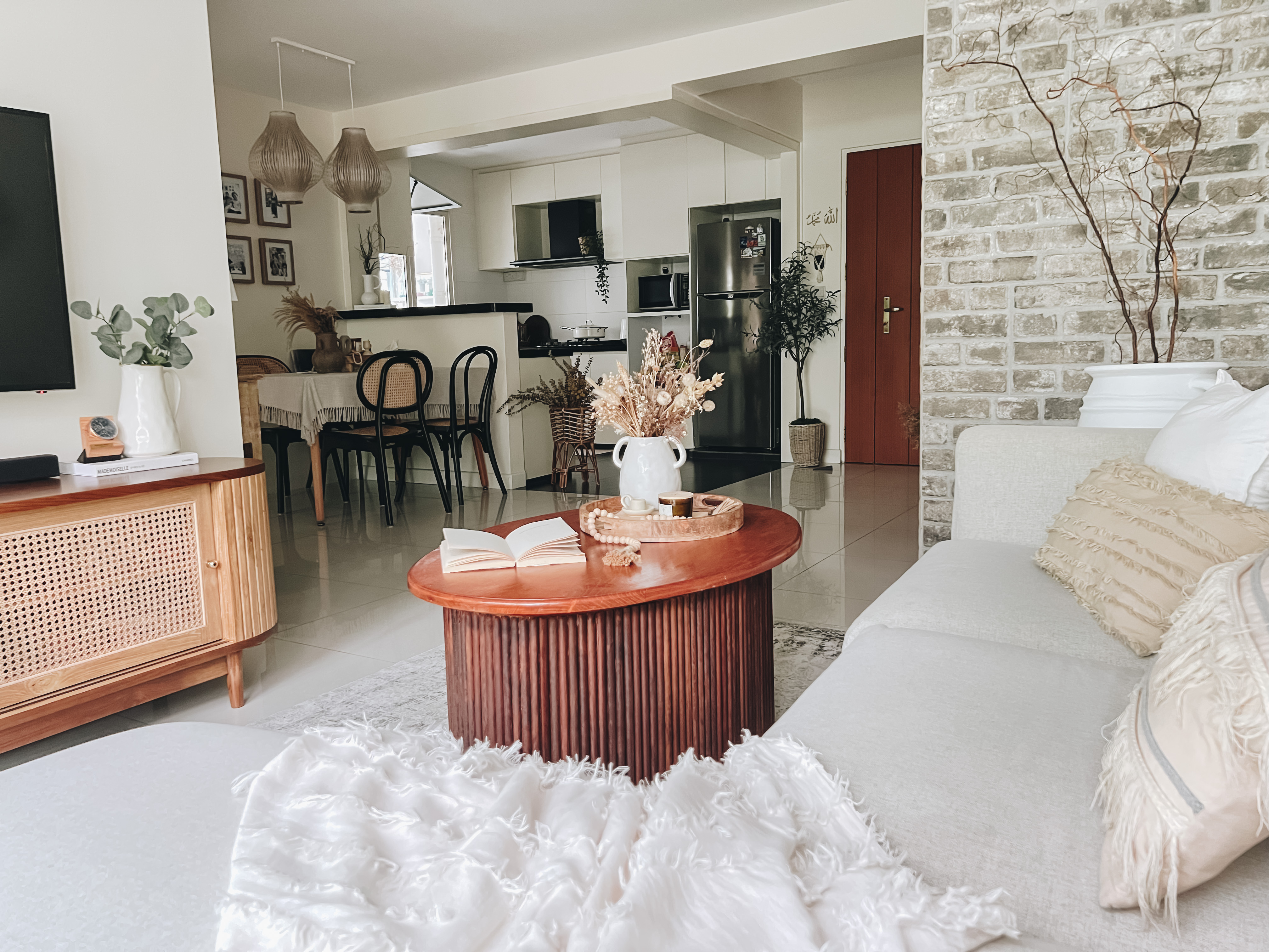 A Boho Paradise Home - Modern living room with minimalist decor, brick wall background, wooden coffee table with books and