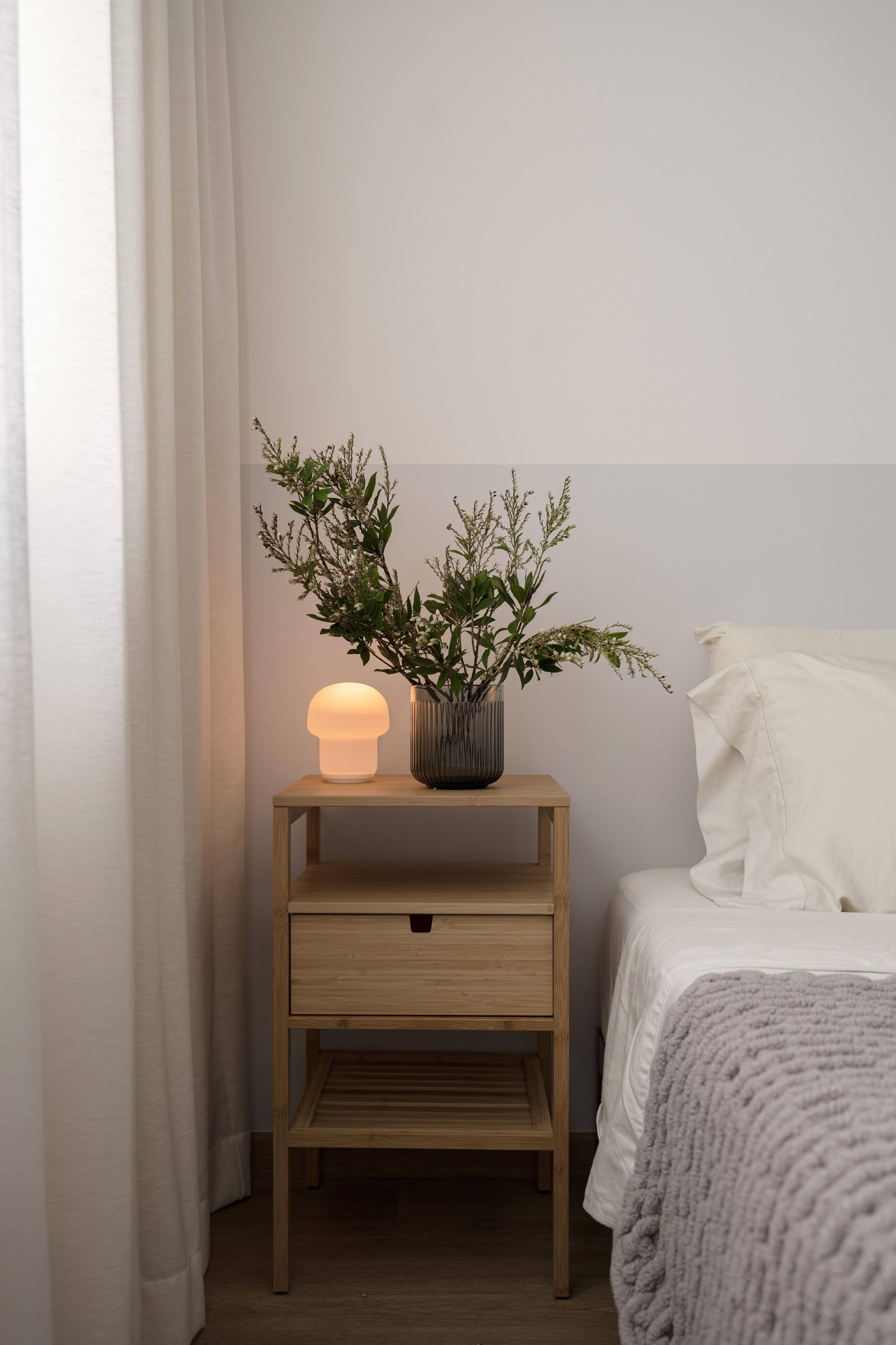Our Calm and Cozy Japandi-themed Home - Wooden nightstand with a lamp, white curtains, green plant in a vase, wooden shelf