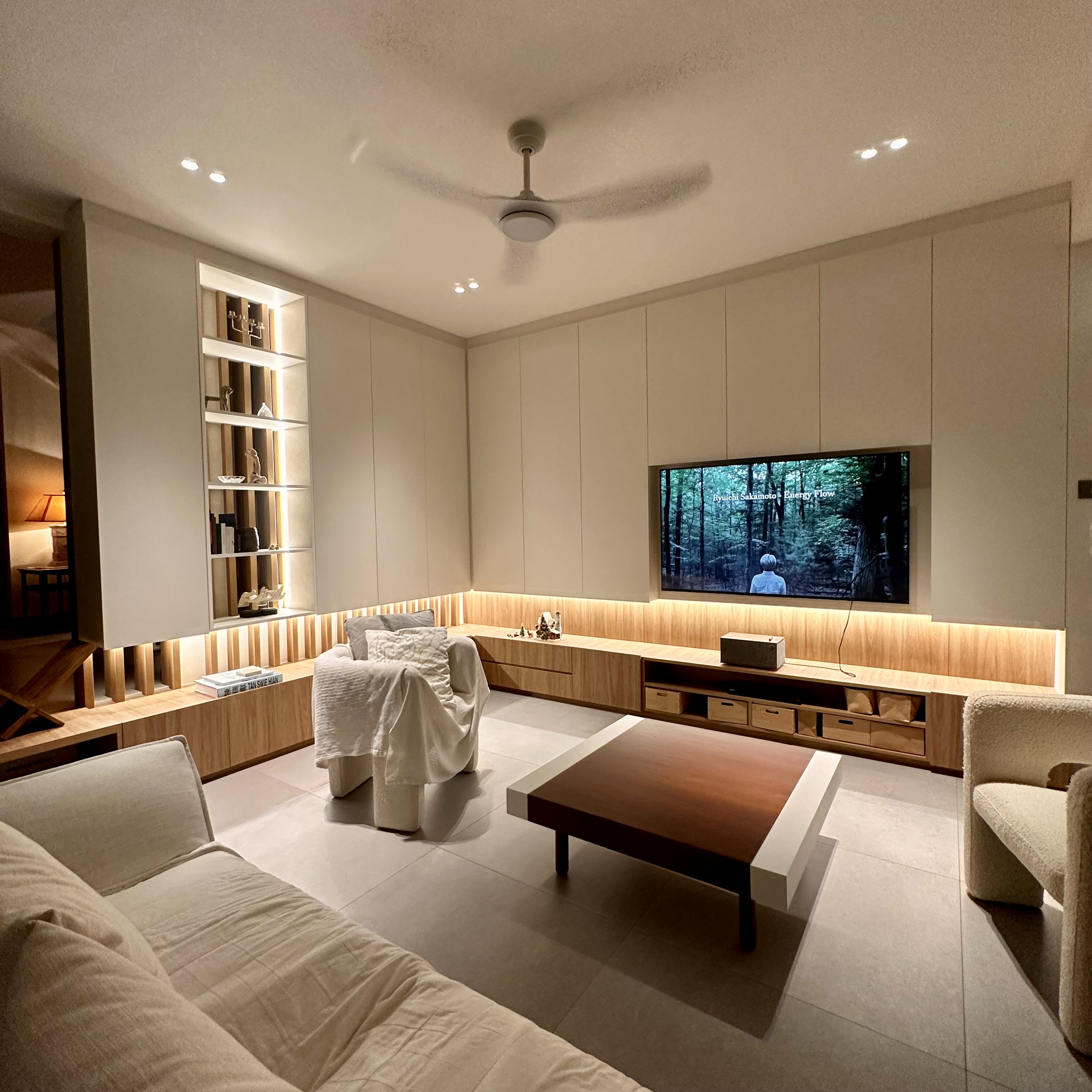 60’s grilles in a newly constructed house - Modern minimalist living room, sleek ceiling fan, built-in shelving, warm ambient