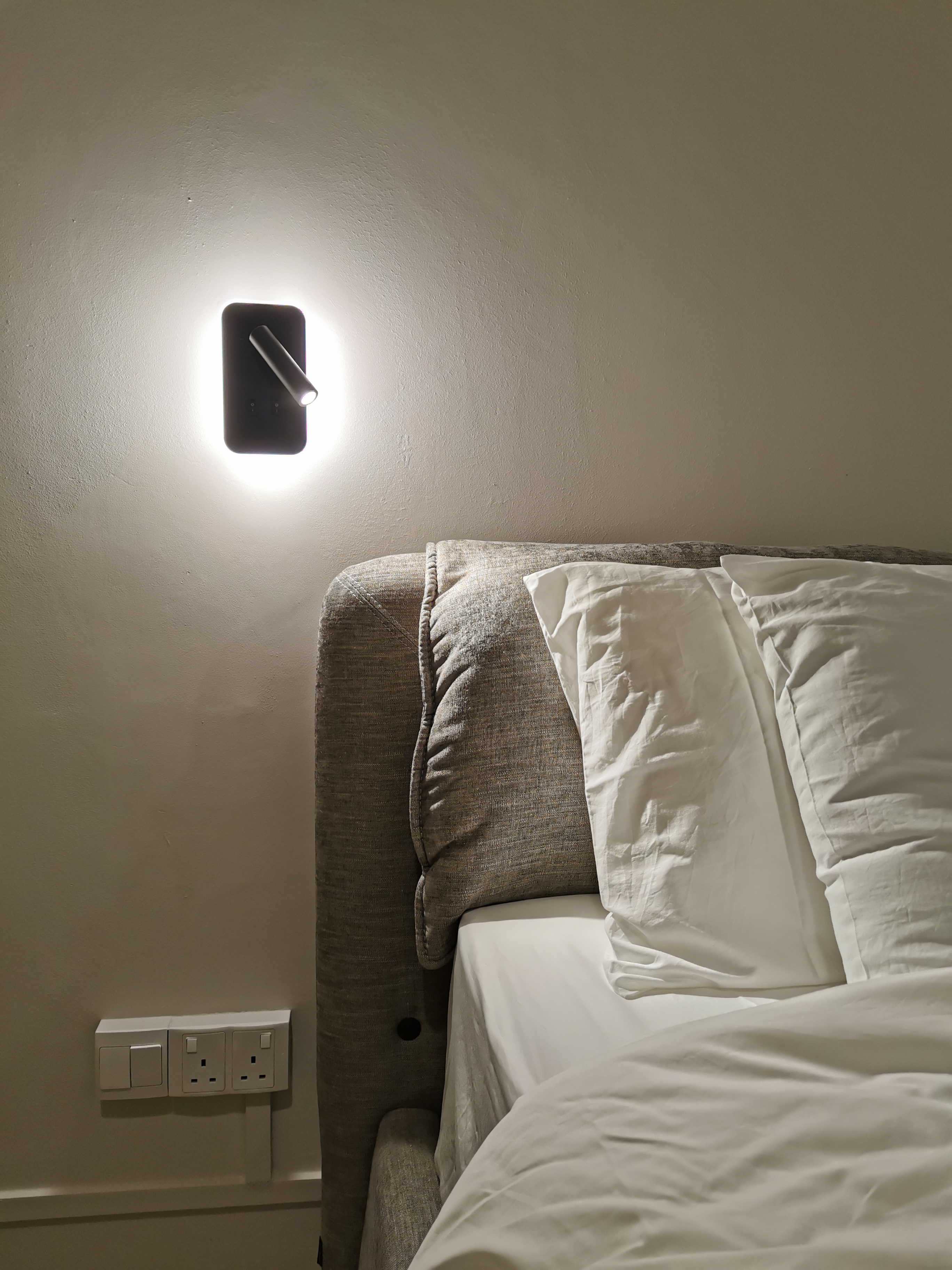 5 Lighting Ideas to Create Mood in your Home - Wall-mounted light fixture, beige textured wall, cozy bedroom ambiance, soft