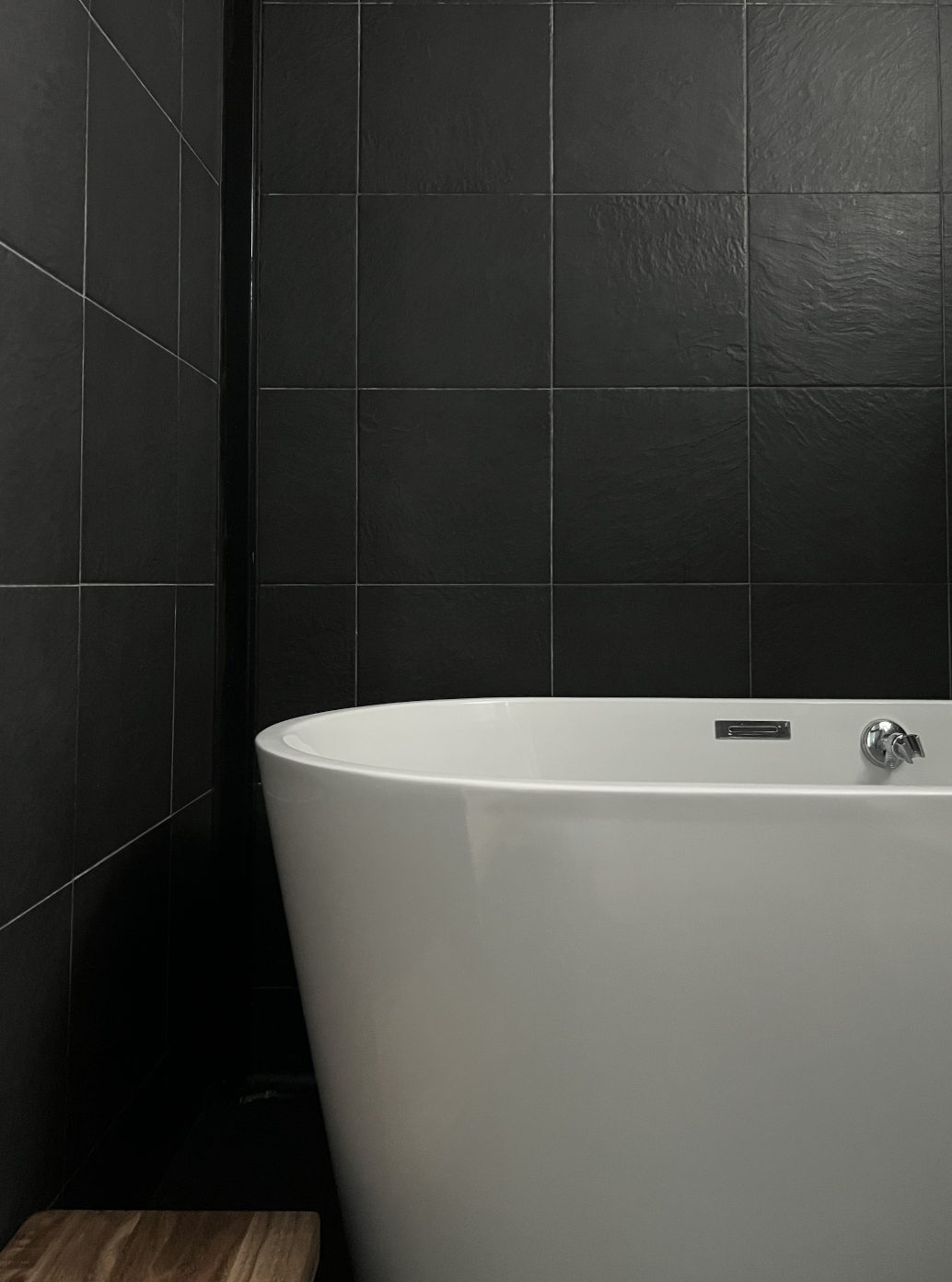 Slow living @slow.ferns - Bathtub with sleek, modern design, white interior, black tiled walls, minimalist aesthetic