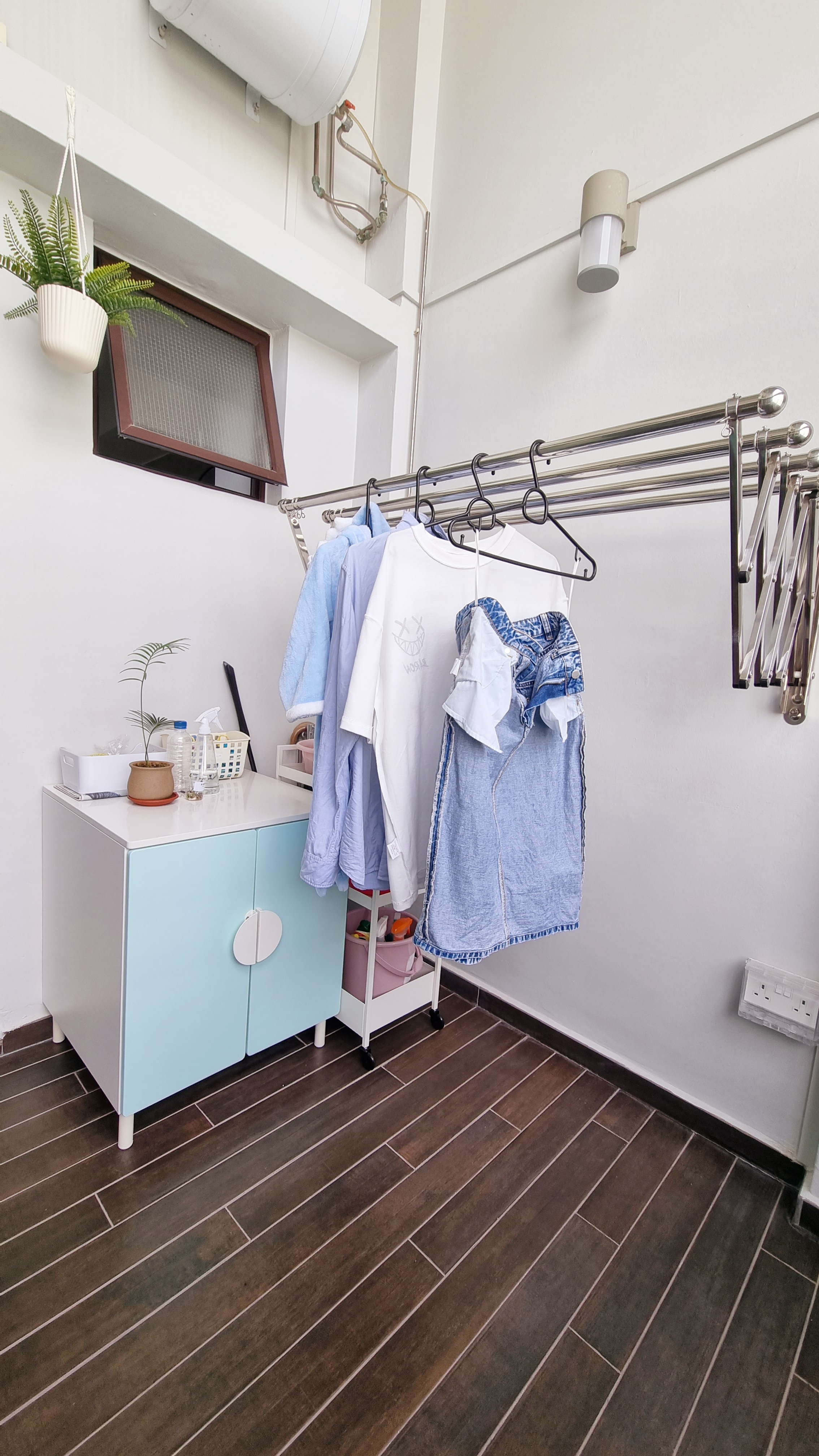 Where we do our laundry with POP OF COLOURS  - Light blue cabinet, white dresser, hanging clothes, white towel, blue denim