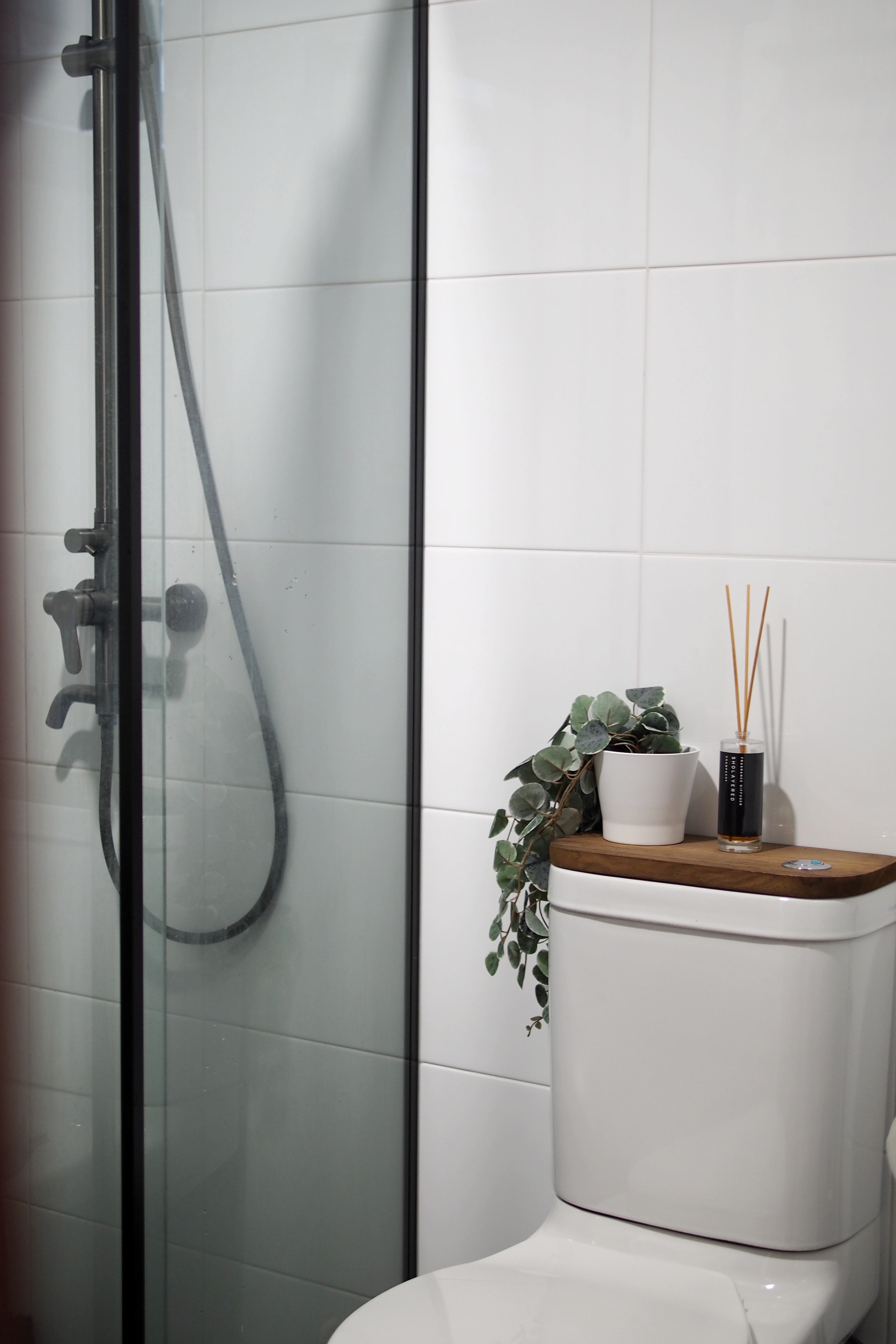 Making a bathroom with HDB fittings work - Glass shower enclosure, white tiled wall, modern design, showerhead, black handle