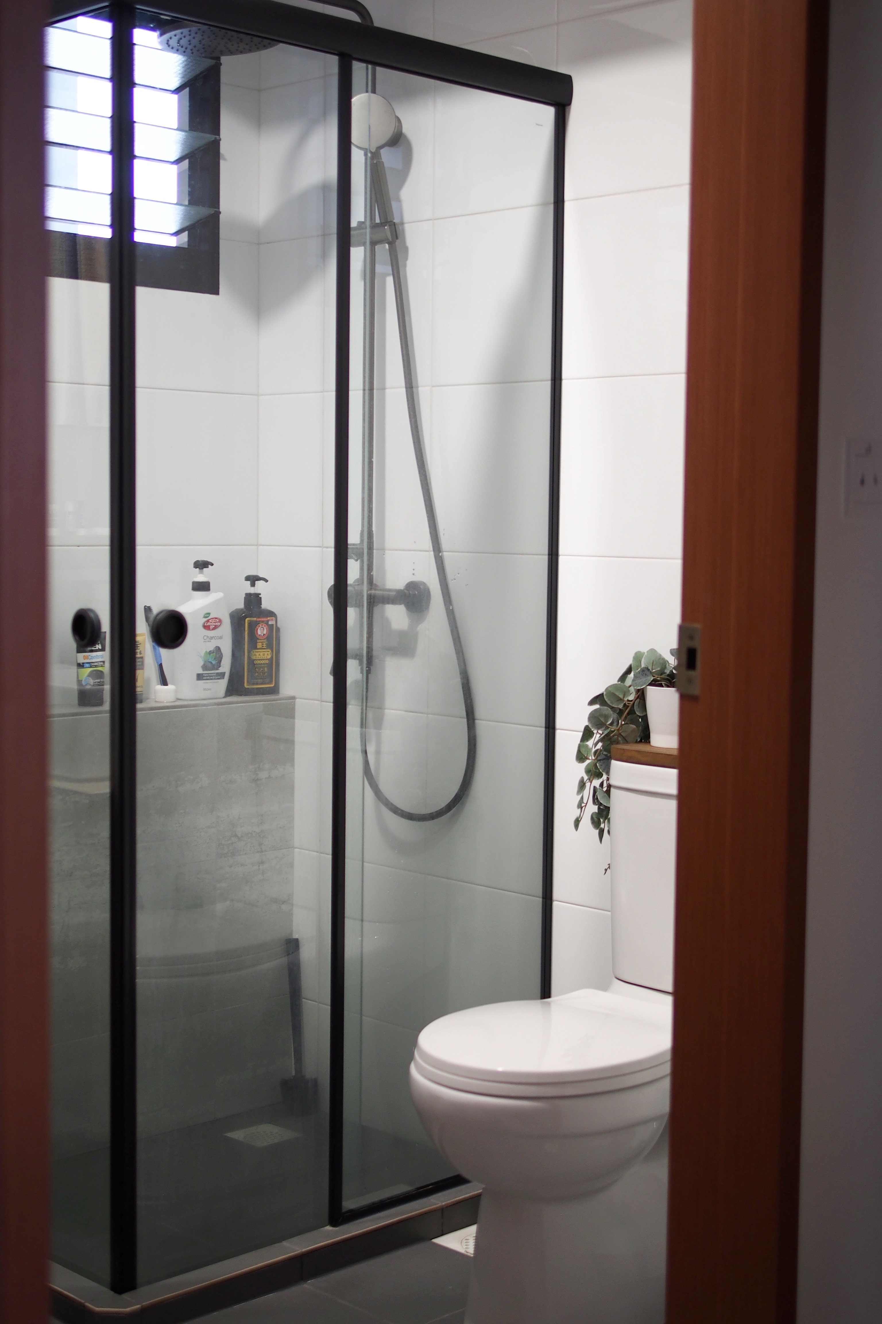 Making a bathroom with HDB fittings work - Glass shower enclosure, white tiled walls, modern design, white toilet, black