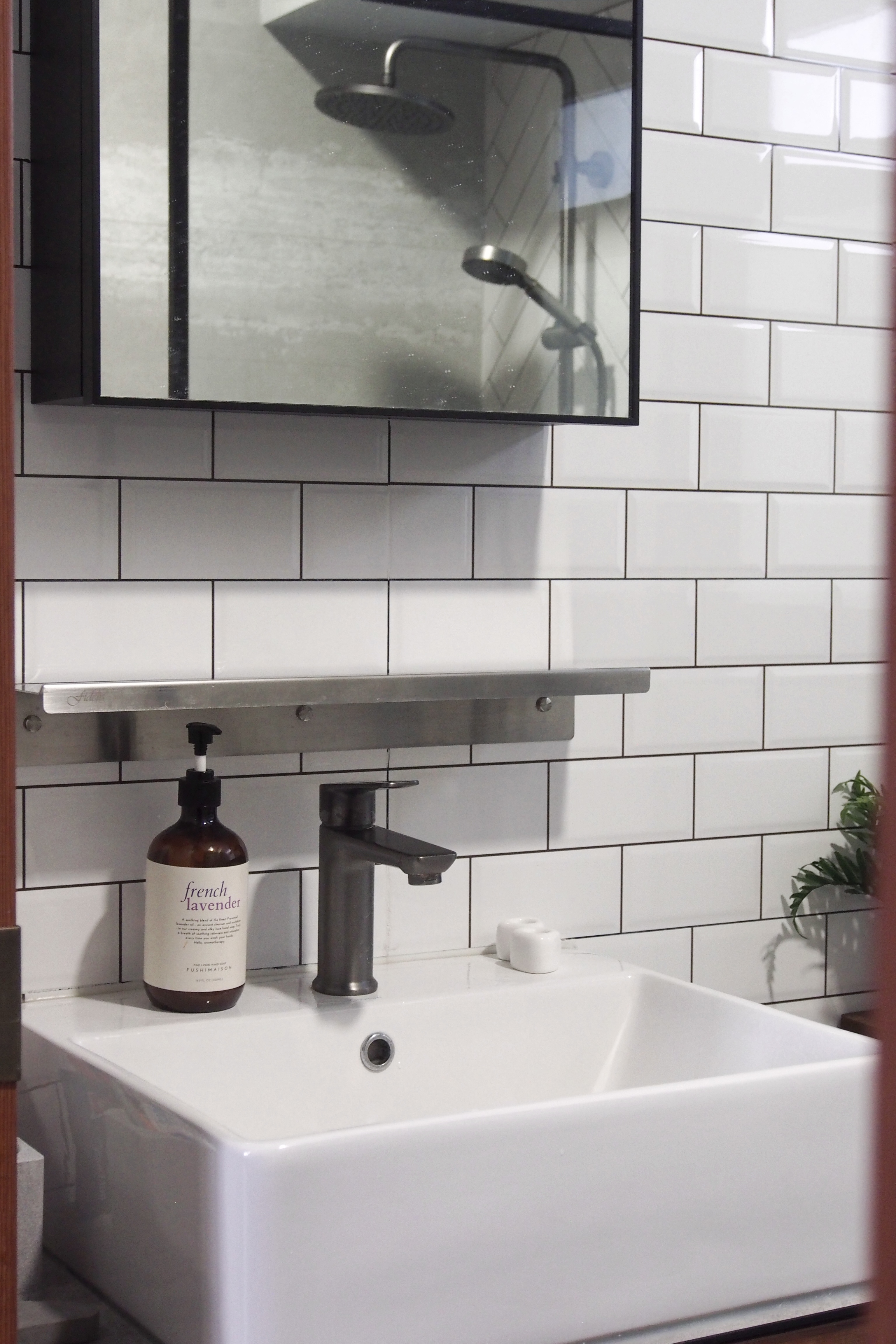 Making a bathroom with HDB fittings work - white bathroom vanity, modern sink, white tiled wall, sleek faucet, wooden door