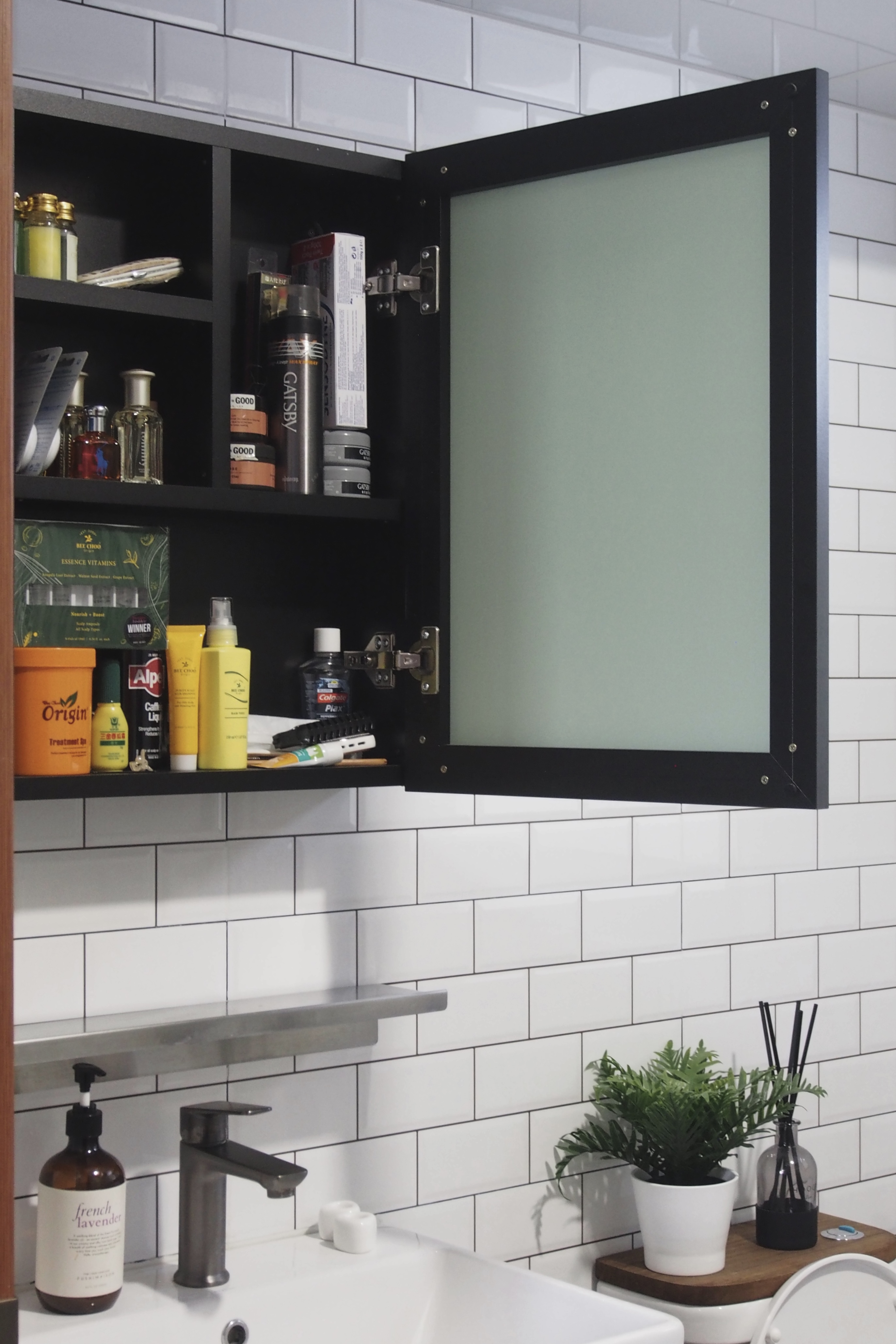 Making a bathroom with HDB fittings work - Black medicine cabinet, white tiled wall, open medicine cabinet, toiletries