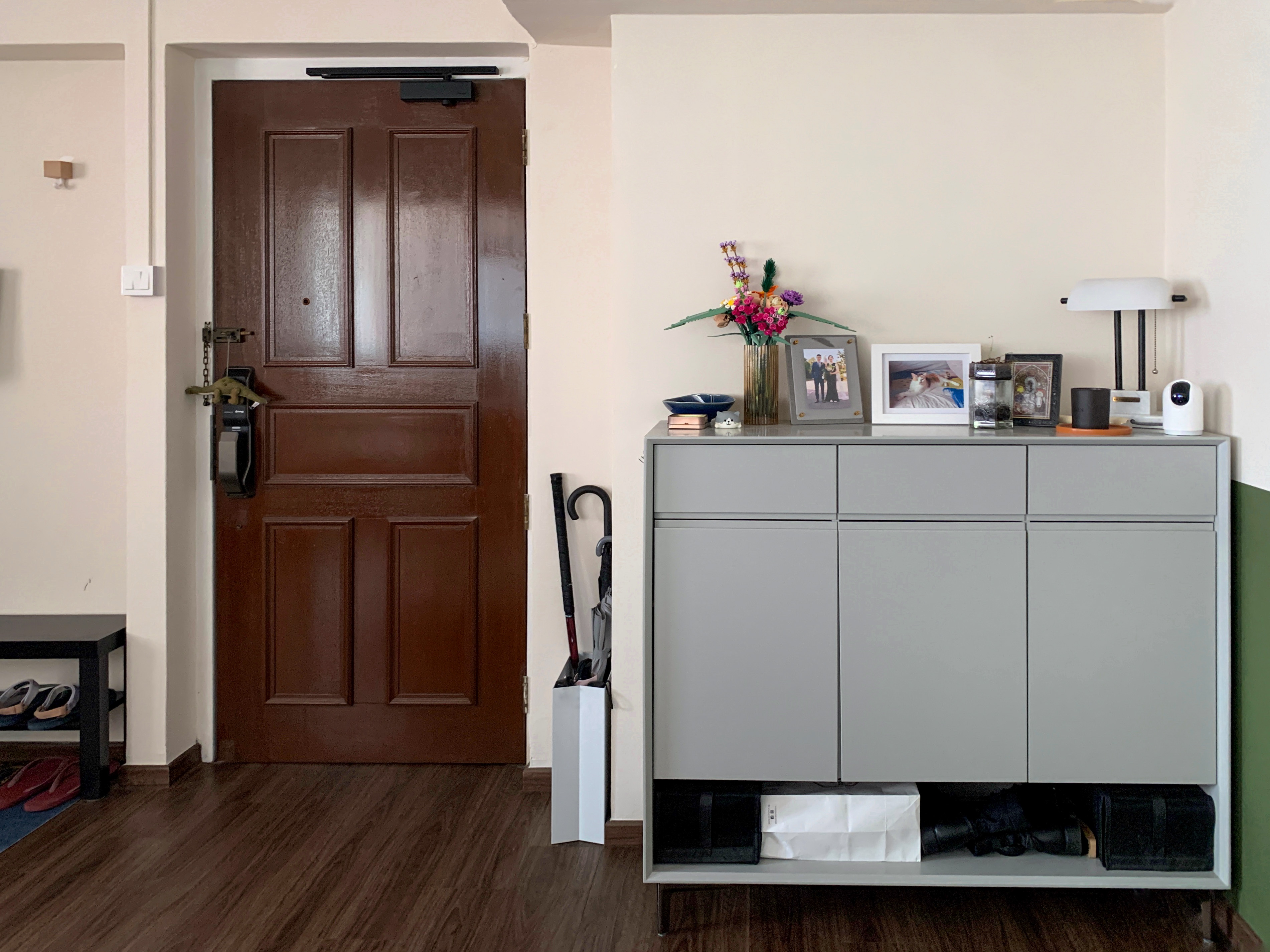 Creating a clean and functional yet personalised entryway  - Wooden door, brown door, gray cabinet, black phone holder, vase