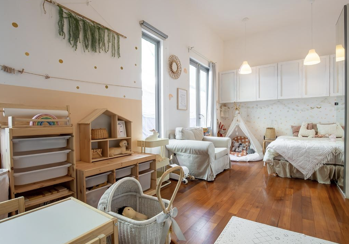 Californian Boho Style Attic Living - Children's playroom with wooden furniture, baby bouncer, storage shelves, colorful