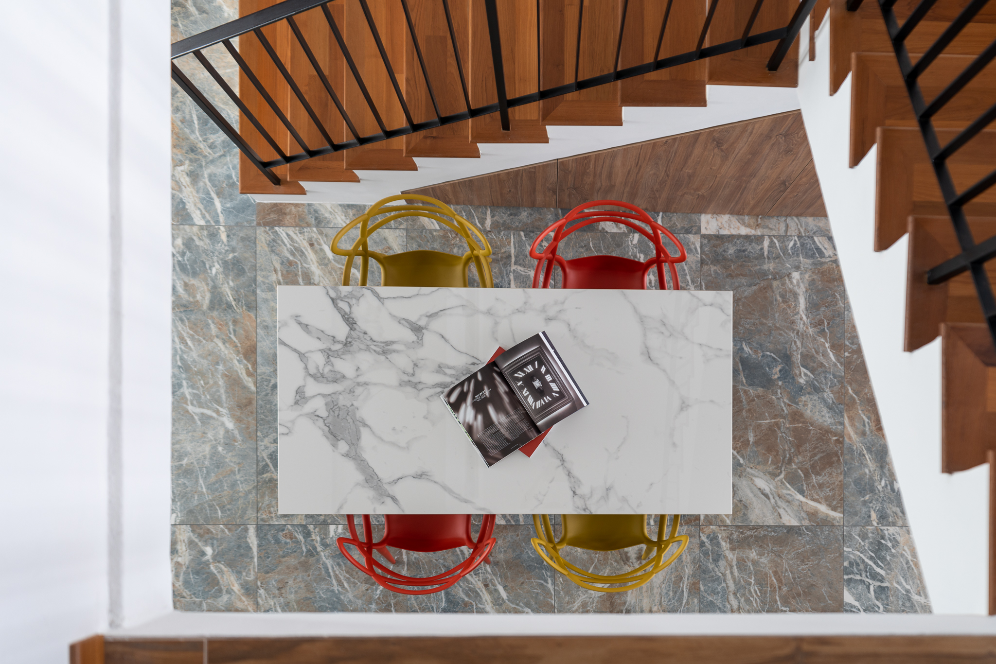 Designing a flexible dining setup - Marble-topped staircase, wooden handrail, modern chairs, colorful chairs, marble floor