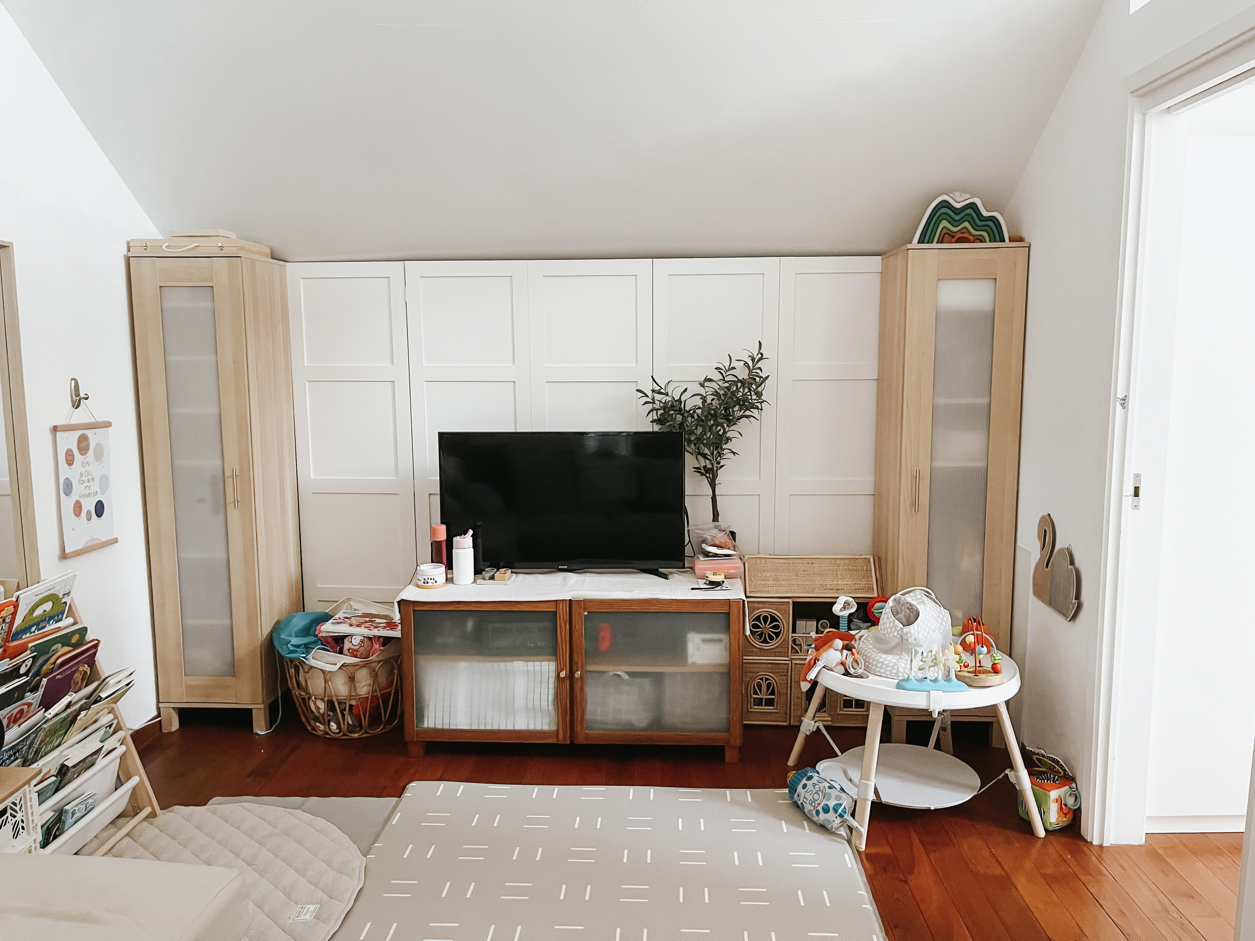 Living Room Makeover under $300 - Wooden cabinet, white walls, slanted ceiling, wooden wardrobe, colorful wall art, white
