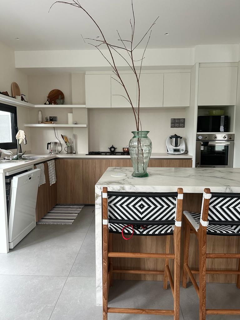 How I plan and organise my kitchen - Modern kitchen with sleek white cabinetry, marble island, wooden bar stools, black and